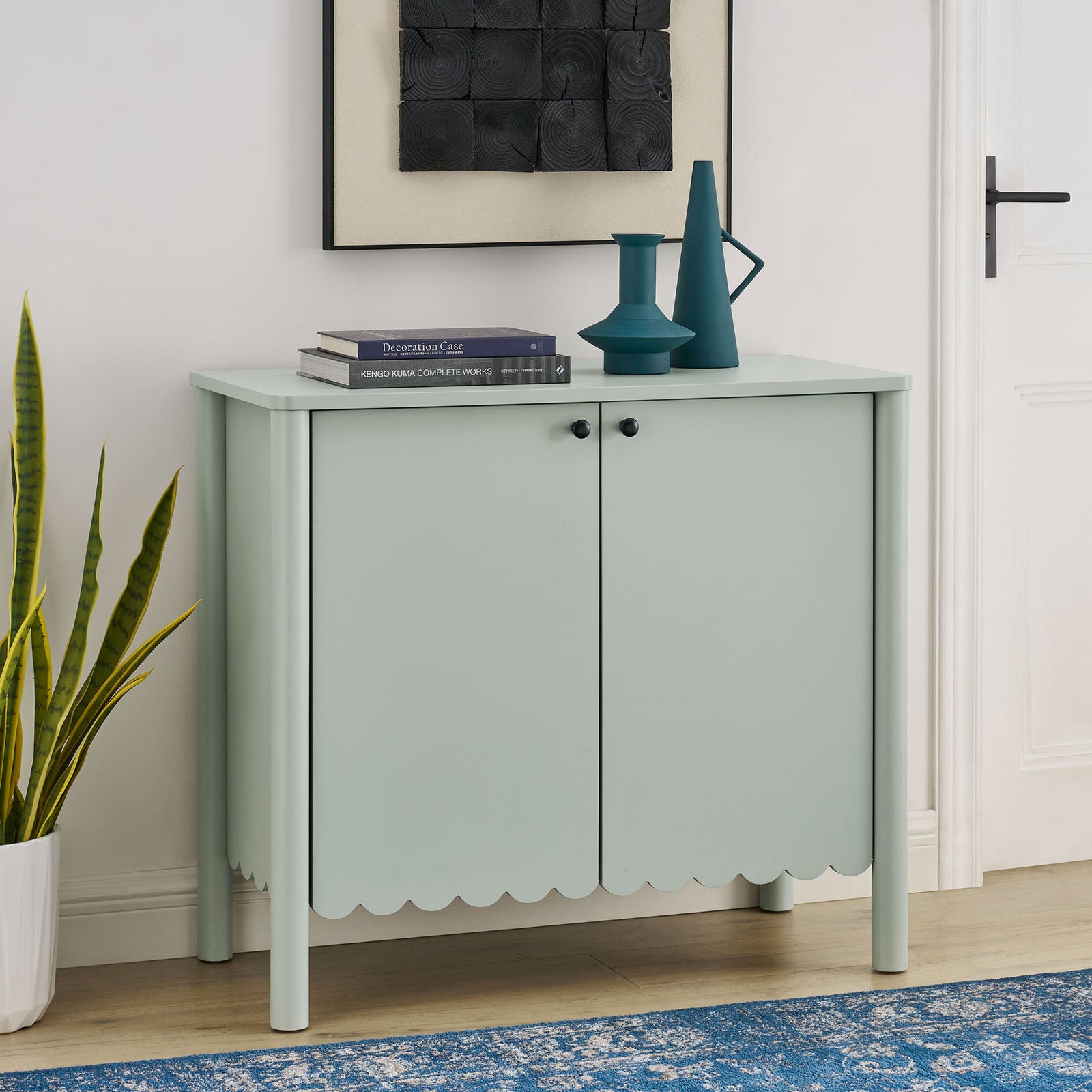 Sage green scalloped cabinet styled in a bright entryway with books, vases, and greenery on display || EEI-7152-SGE || front_room
