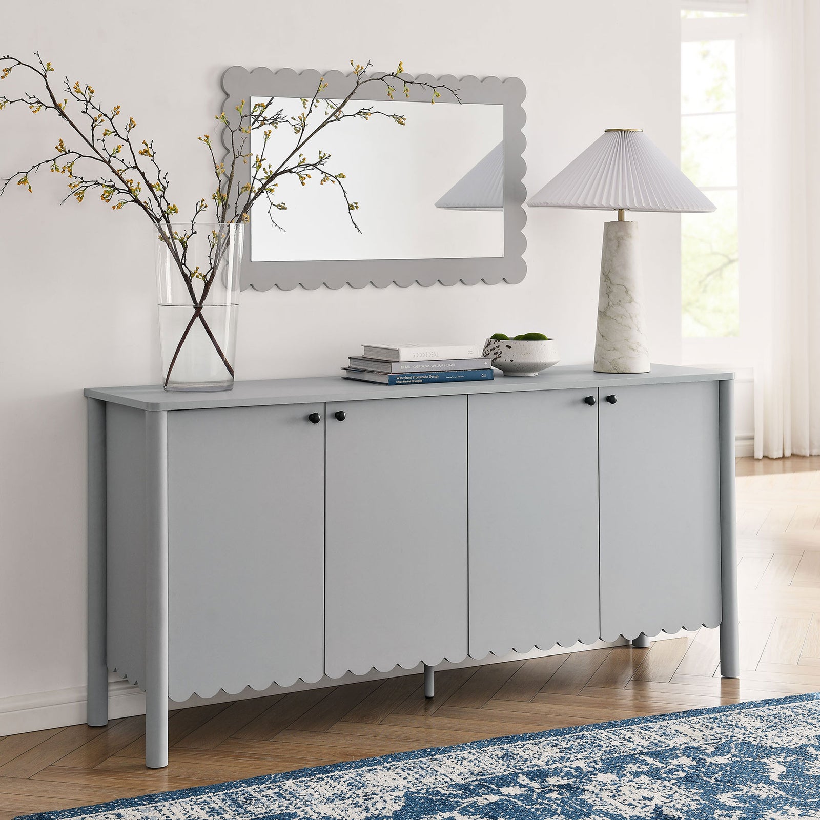 Emmeline sideboard styled in an entryway with mirror, lamp, and tall vase, adding soft curves and hidden storage || EEI-7153-LGR || front_angle_room