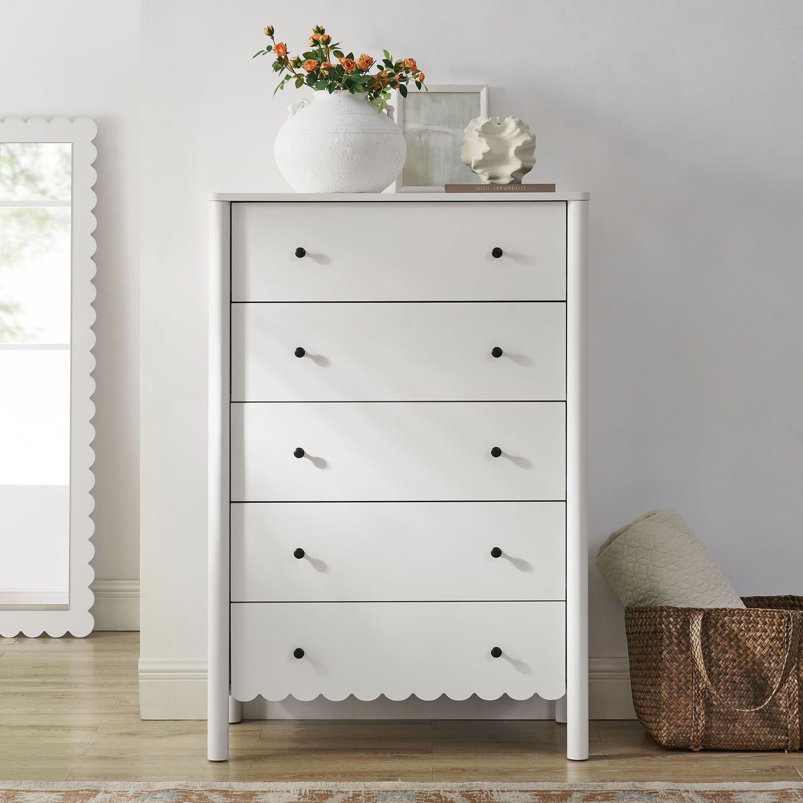 White scalloped 5-drawer chest styled with decor brings soft modern charm to a bright, airy space. || EEI-7156-WHI || front_room
