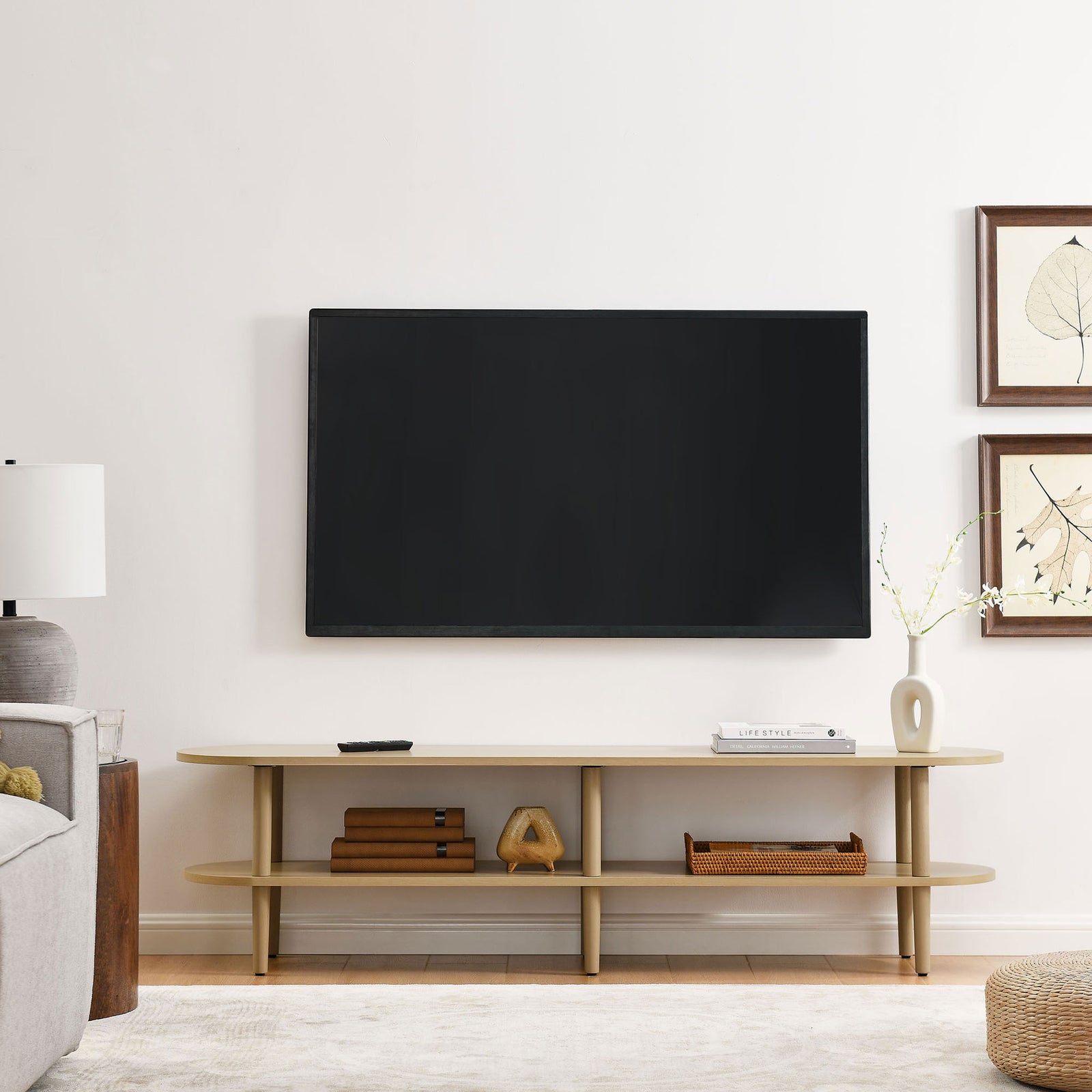 Light oak oval TV stand anchoring a modern living room under a wall mounted flat screen TV || EEI-7158-OAK || front_room