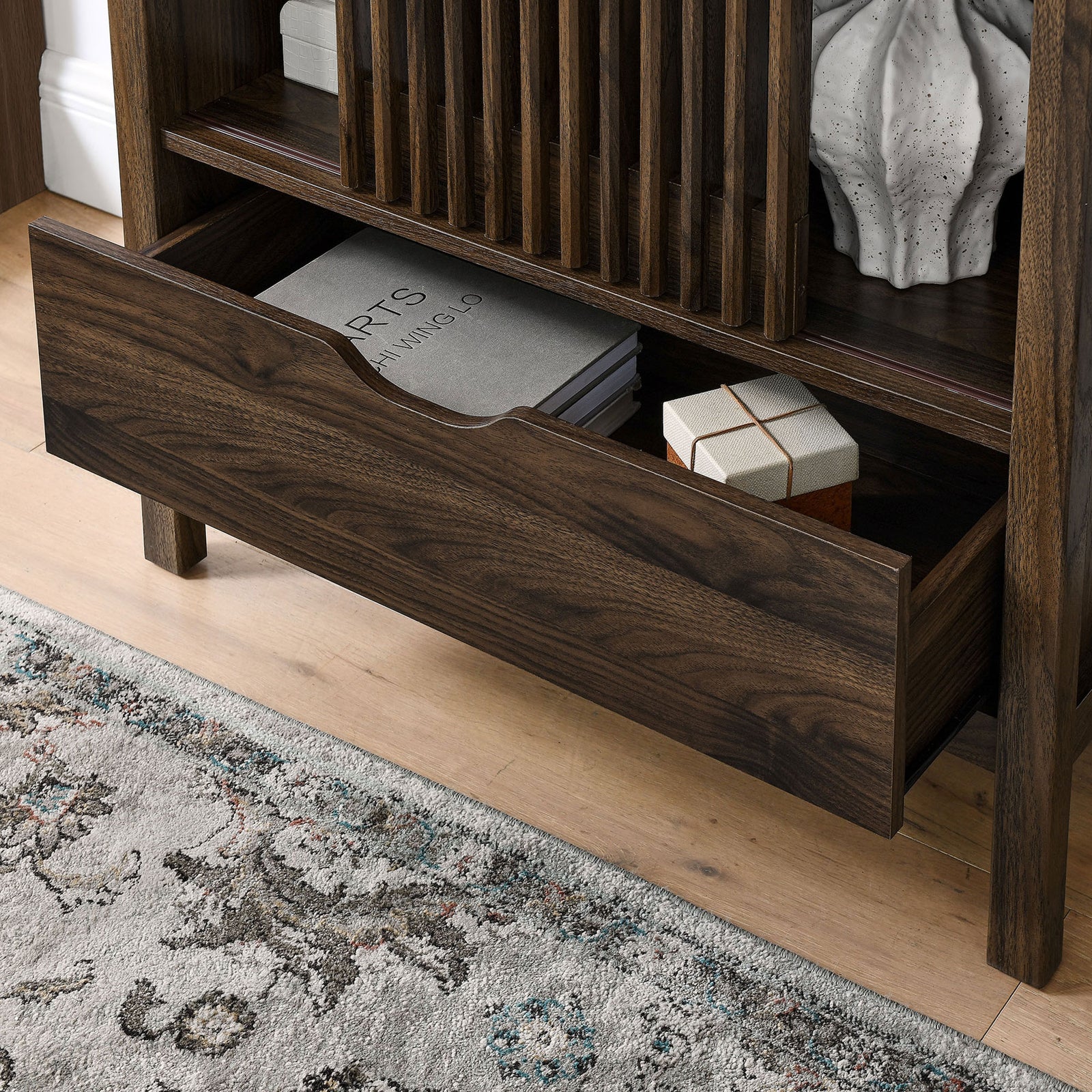 Open drawer of the walnut cabinet neatly storing books and decor in a modern room. || EEI-7167-WAL || storage_open_room