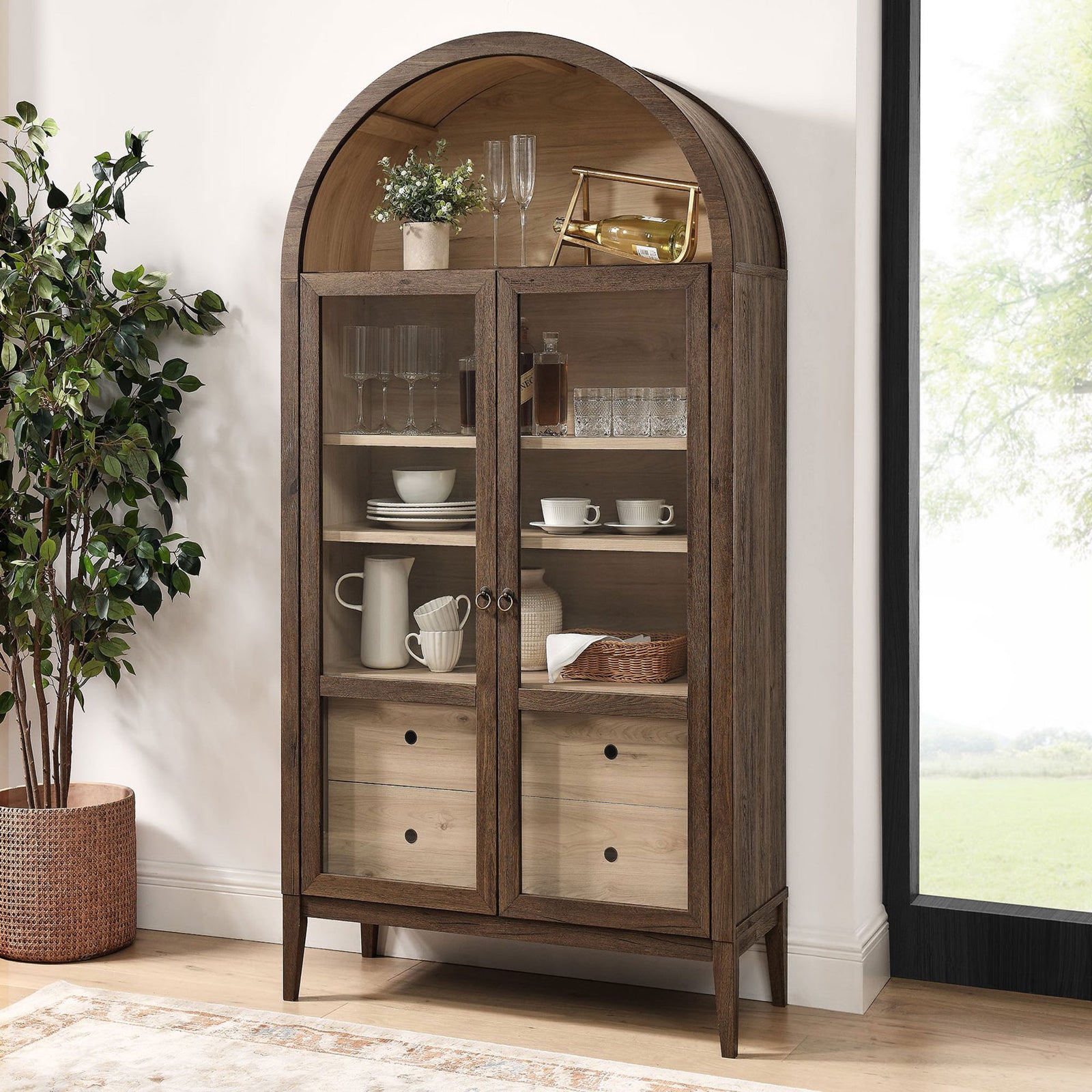 Walnut and light oak display cabinet arranged with glassware and bar accessories near a window || EEI-7168-WAL-LOA || front_angle_room