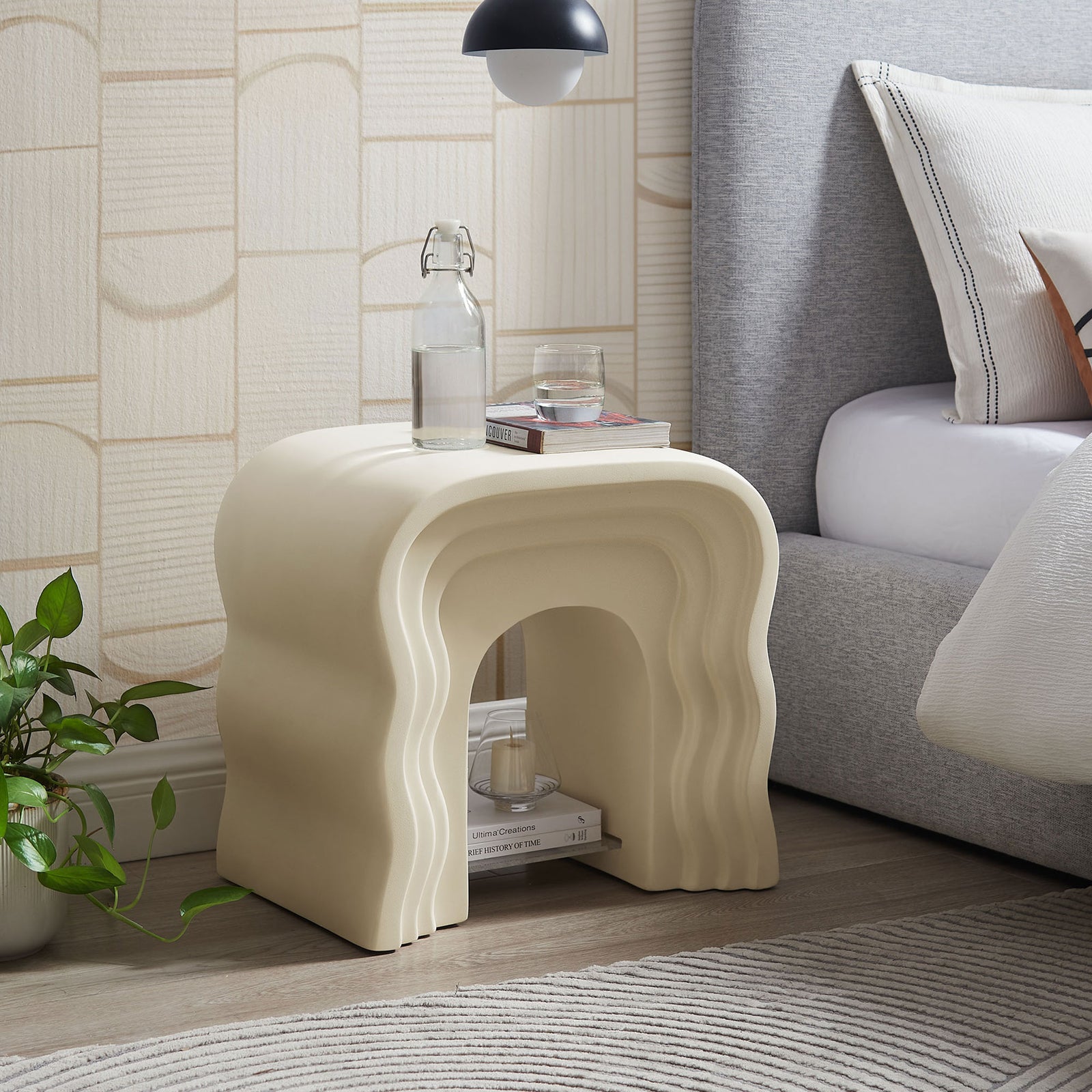 Ivory squiggle side table used as a bedside accent, pairing sculpted curves with a movable acrylic shelf || EEI-7171-IVO || front_angle_room
