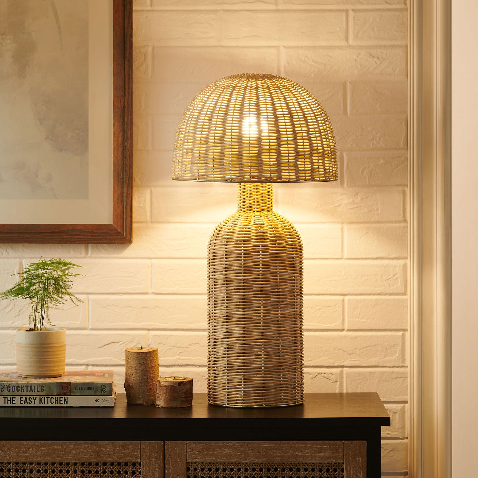 Natural rattan table lamp illuminating the room with a soft inviting ambient glow || EEI-7191-NAT || front_on_room