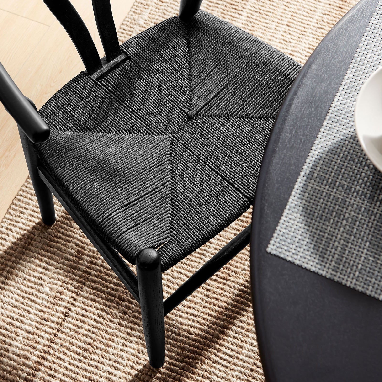 Overhead view of the black woven rope seat paired with a textured rug and dining table || EEI-7200-BLK-BLK || detail_room