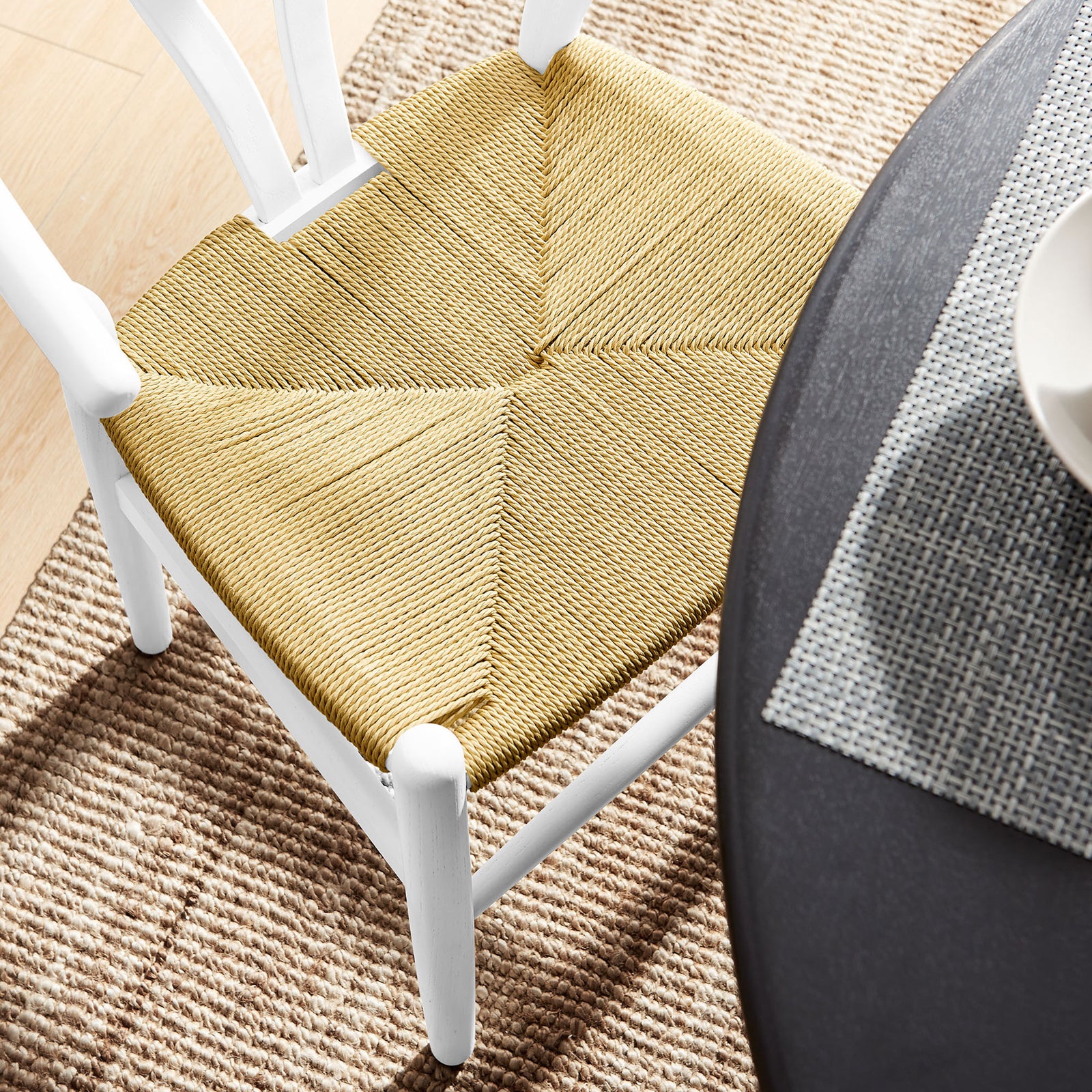 Natural rope seat and white wood frame styled beside a round dining table on a woven area rug. || EEI-7200-WHI || detail_room