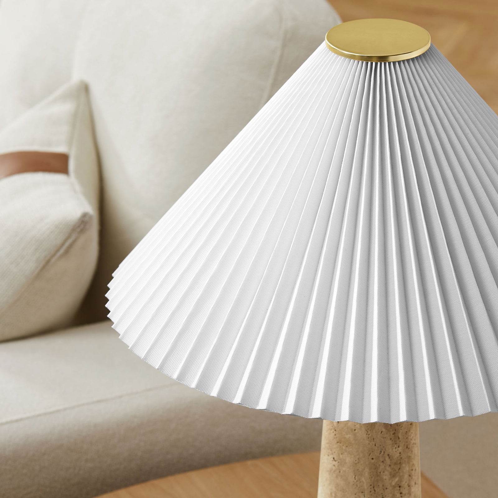 Pleated shade and brass cap add sculptural texture above the travertine base in a cozy living room setting || EEI-7215-TRV || shade_room
