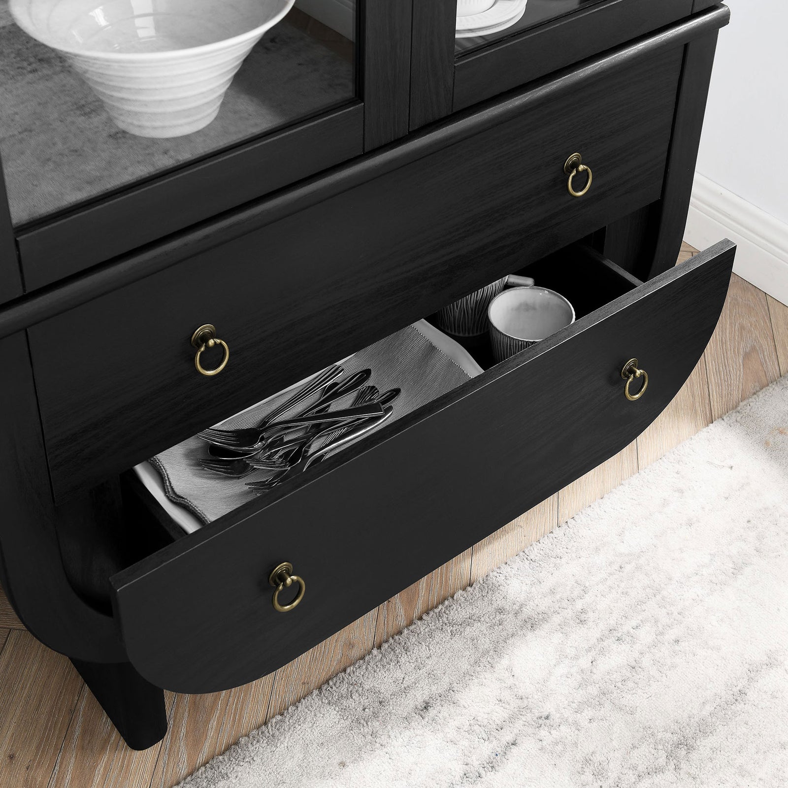 Open drawers of the Nyx cabinet neatly organizing flatware and dishes above a textured area rug || EEI-7216-BLK-LOA || storage_open_room