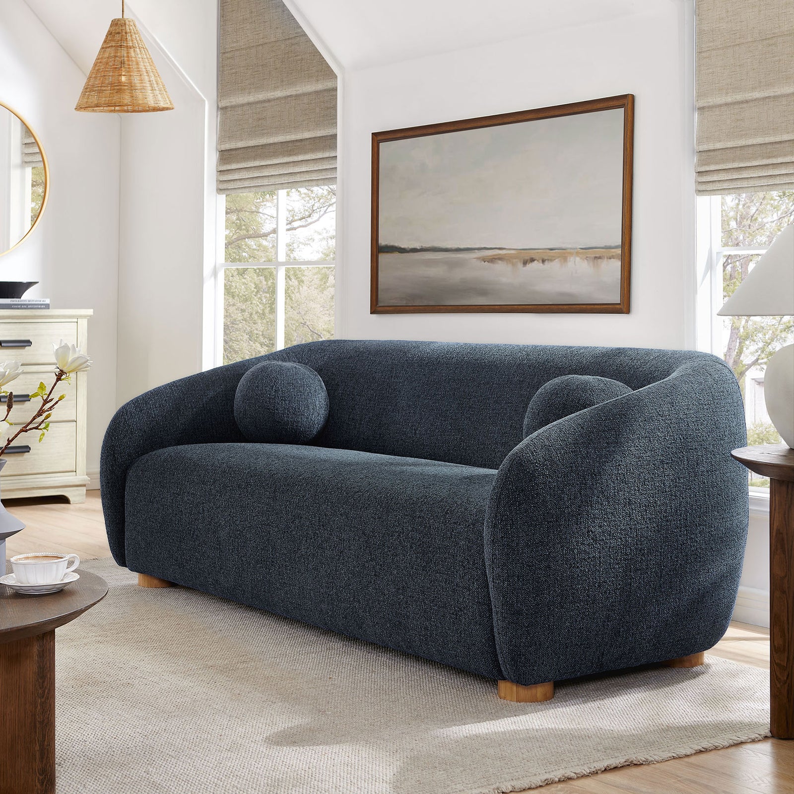 Navy curved Holland sofa styled in a modern living room with artwork, wood accents, and neutral rug. || EEI-7217-NAV || front_angle_room