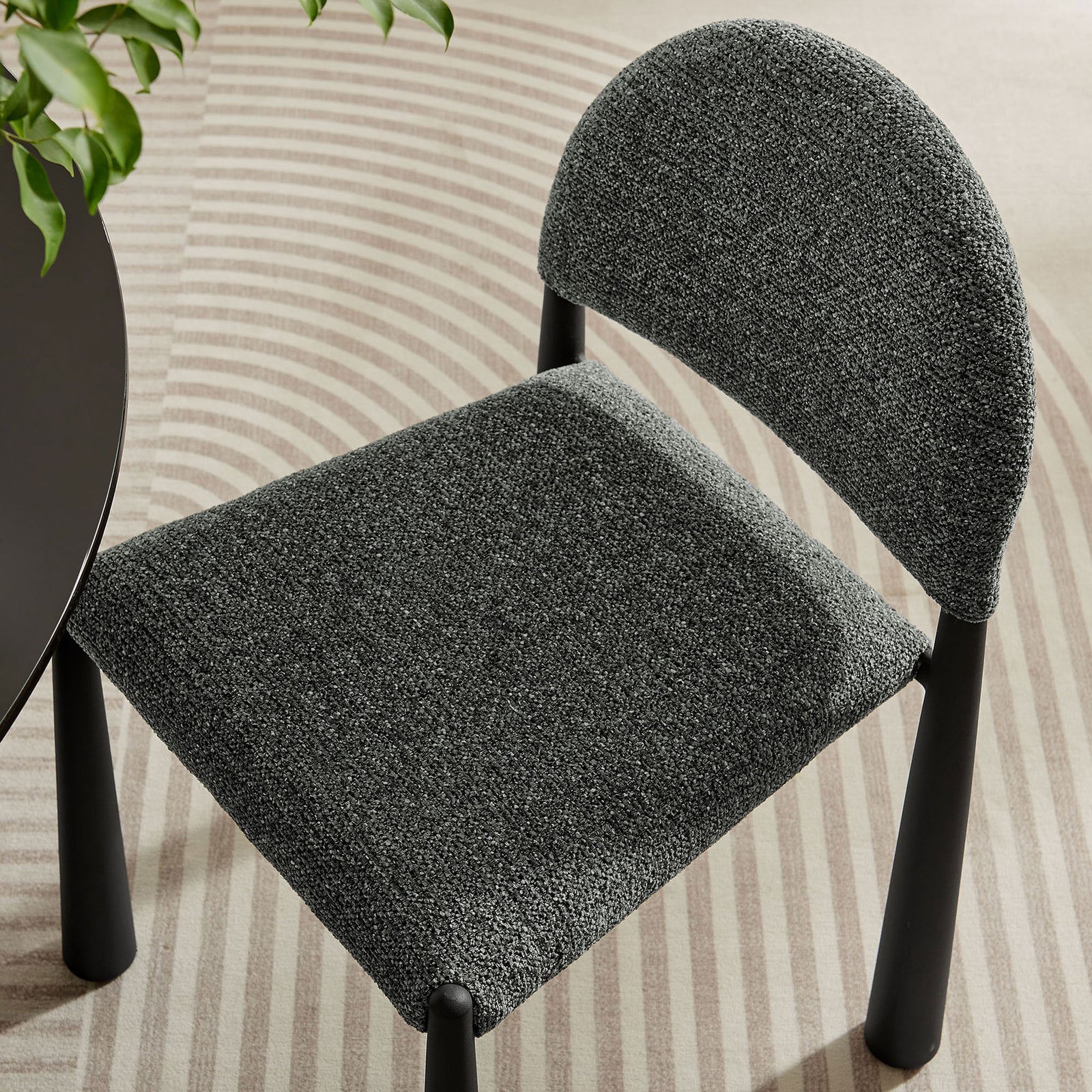 Black anthracite dining chair seat and back shown atop patterned rug beside a modern round table. || EEI-7220-BLK-ANT || detail_room