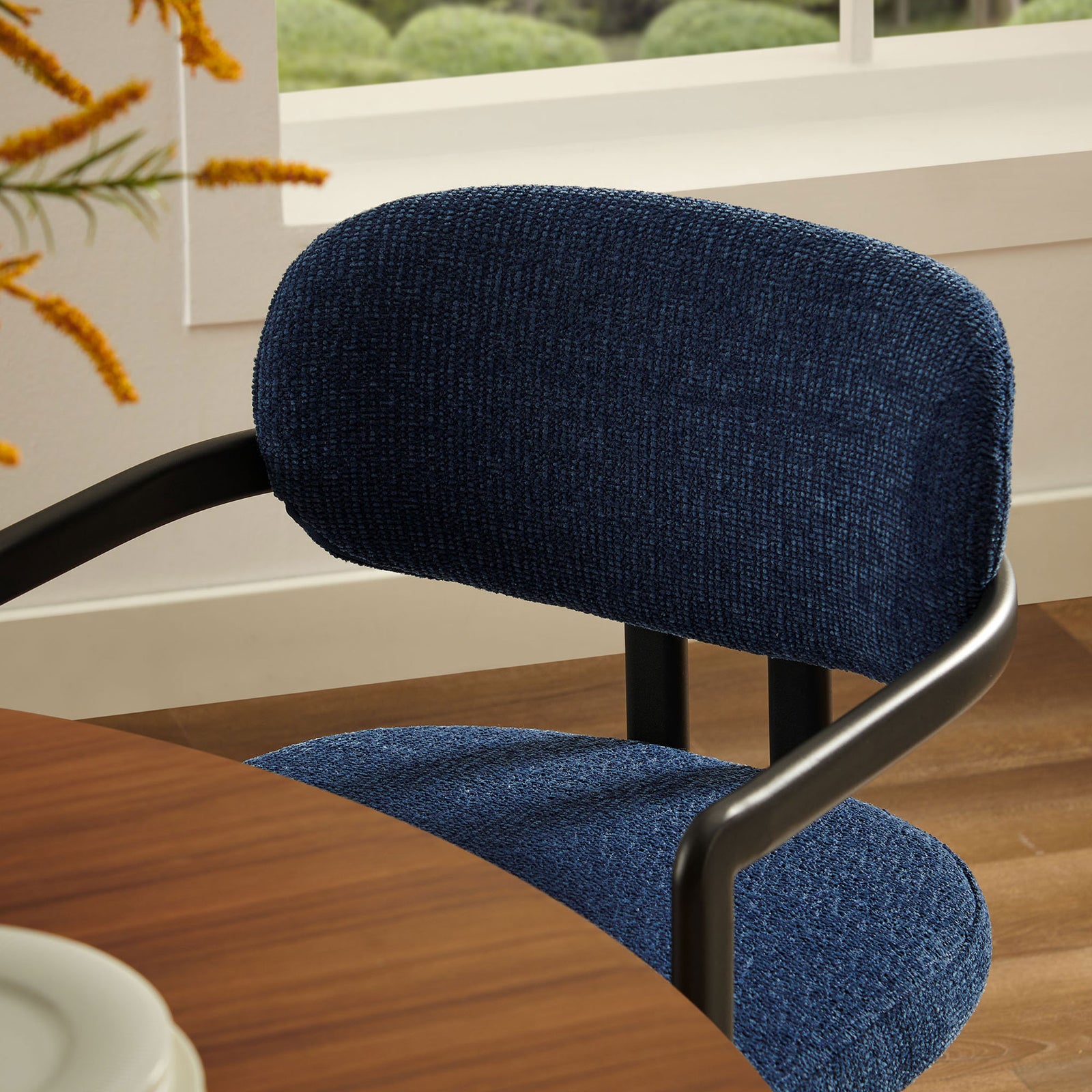 Navy barrel chair tucked at a dining table, emphasizing the cozy woven fabric and curved backrest. || EEI-7229-BLK-NAV || detail_room
