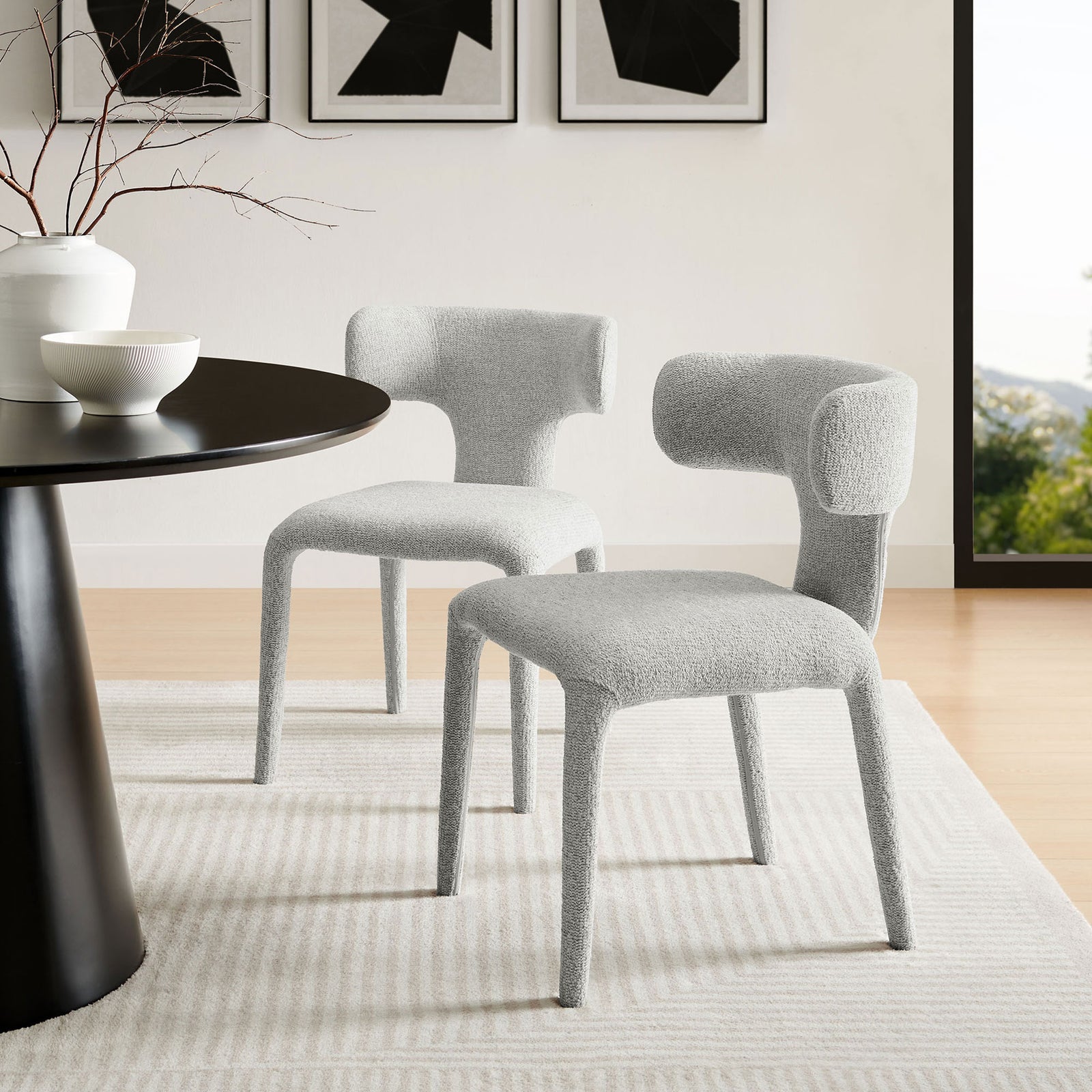 Two dove gray boucle dining chairs styled around a modern black dining table in a bright airy room || EEI-7230-DOV || front_angle_multi_room