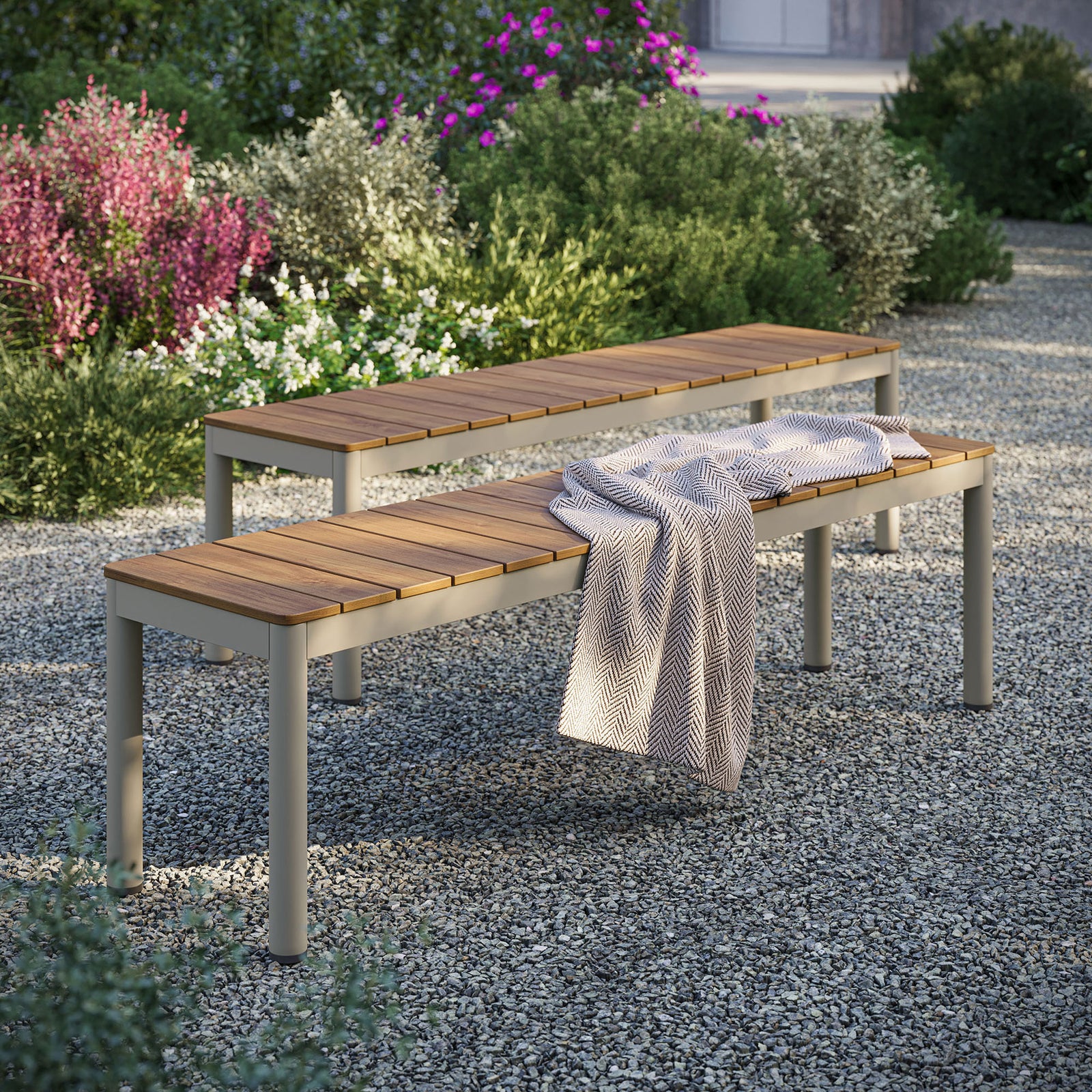 Two Finn patio benches arranged on gravel with blooming garden backdrop for relaxed outdoor seating || EEI-7238-NAT || front_angle_multi_room