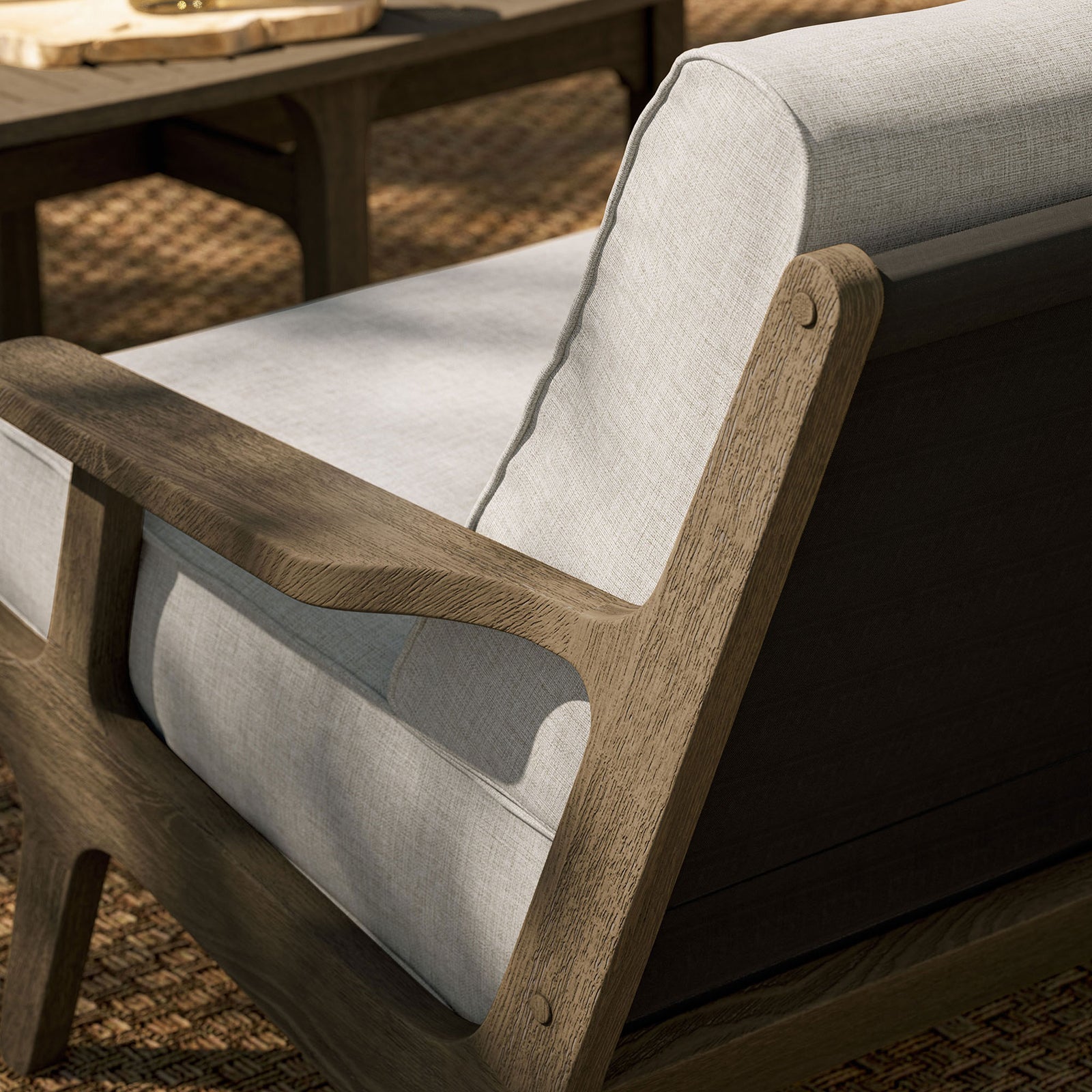 Saratoga loveseat on woven outdoor rug emphasizing the warm teak frame and light pebble cushions. || EEI-7247-WGR-PEB || detail_room