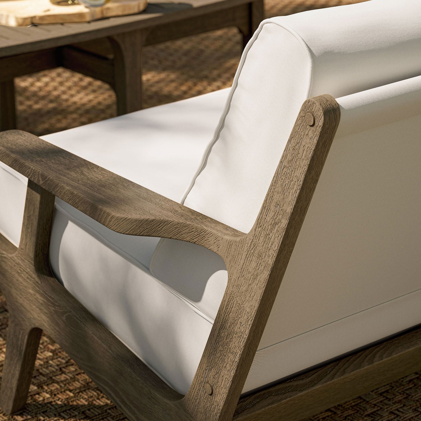 Saratoga loveseat on woven patio rug showcasing the warm teak frame and bright white cushions. || EEI-7247-WGR-WHI || detail_room