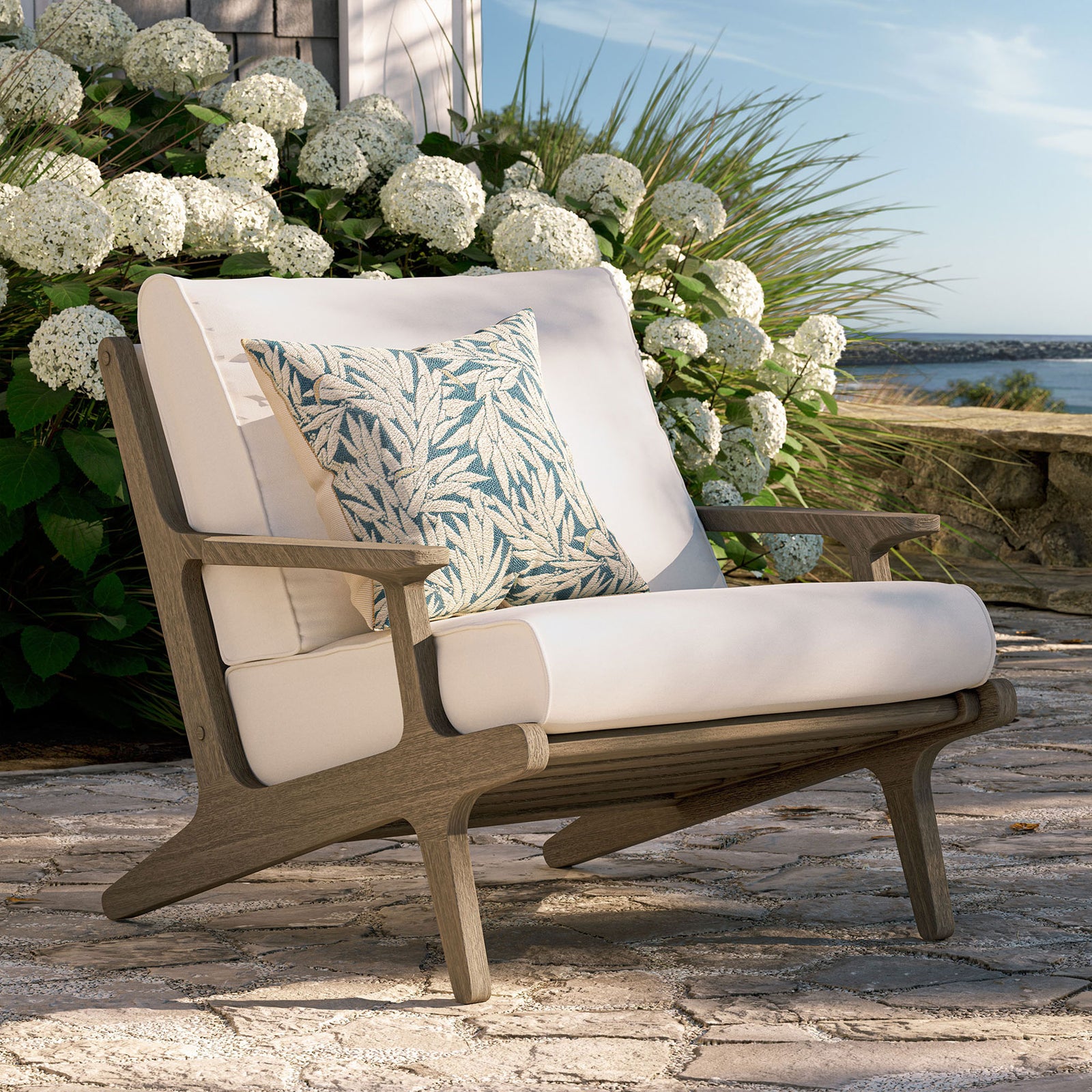 Saratoga white armchair creating a bright teak lounge spot on a breezy stone patio || EEI-7248-WGR-WHI || front_angle_room