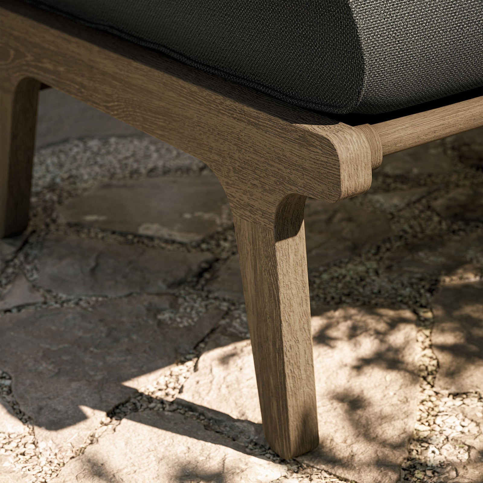 Weathered teak ottoman leg on stone patio, showing sturdy construction for outdoor durability || EEI-7250-WGR-FLI || leg_room