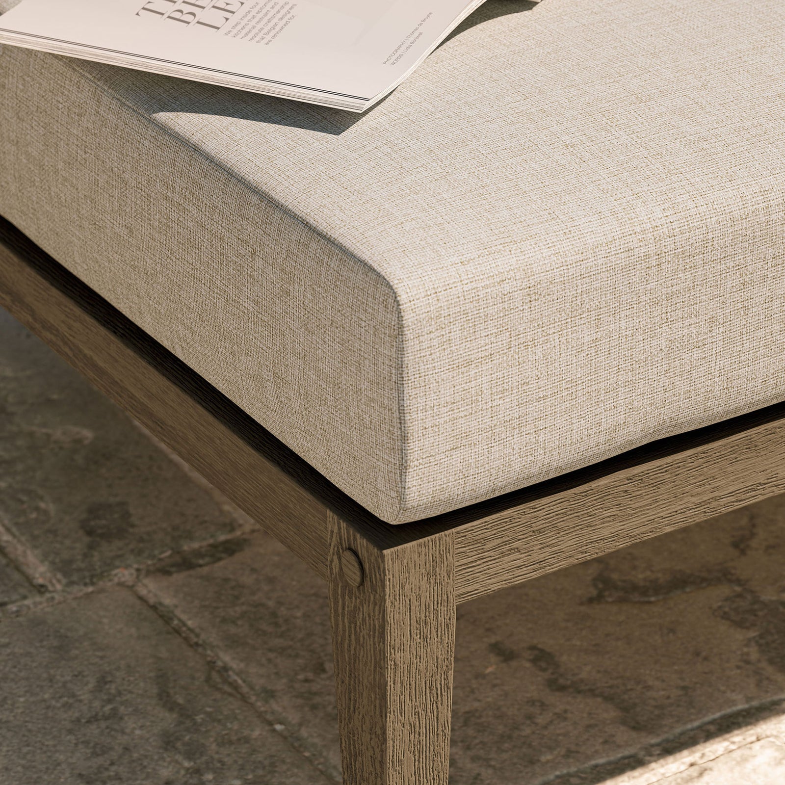 Textured beige cushion and teak base bring relaxed comfort to an outdoor stone patio setting || EEI-7255-WGR-PEB || detail_room