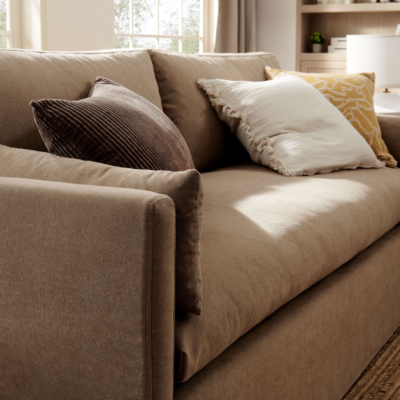 Almond slipcovered sofa seat with layered textured throw pillows creating a cozy, inviting lounge spot. || EEI-7260-ALM || detail_room