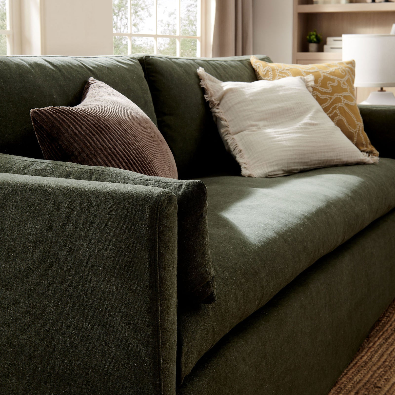Sage green sofa styled with layered accent pillows, emphasizing the plush bench cushion in a bright room || EEI-7260-SGE || detail_room