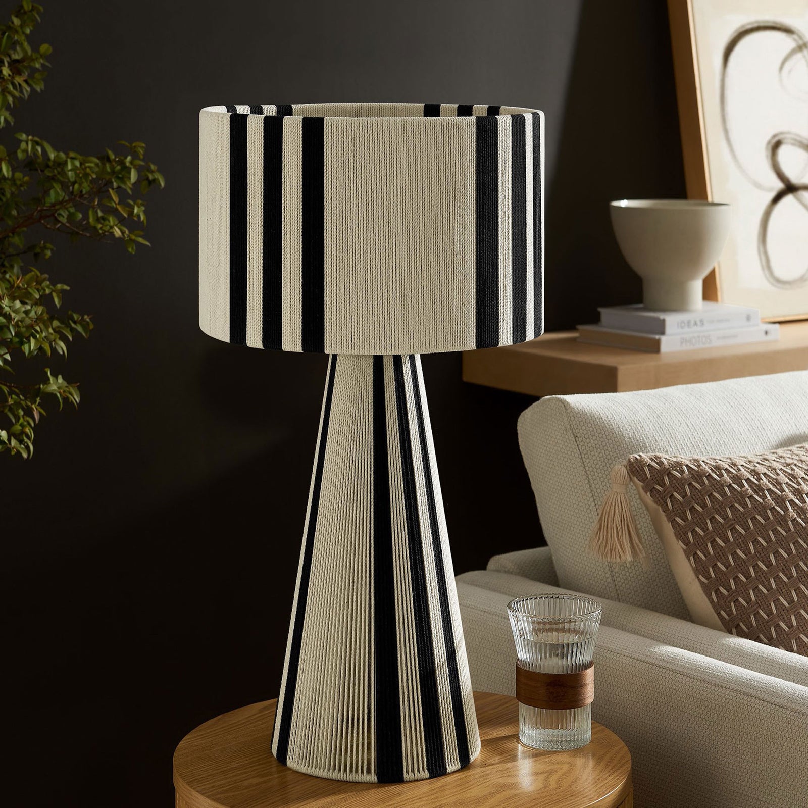 Black striped cotton table lamp styling a side table with refined, modern flair. || EEI-7262-BLK || front_angle_room
