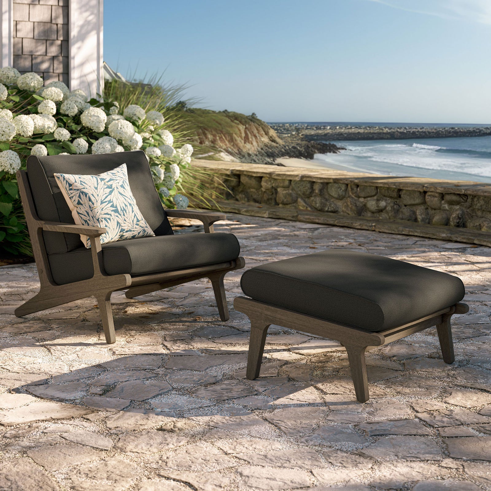 Saratoga flint gray lounge chair and ottoman creating a cozy teak seating nook on a stone patio || EEI-7268-WGR-FLI || front_angle_room