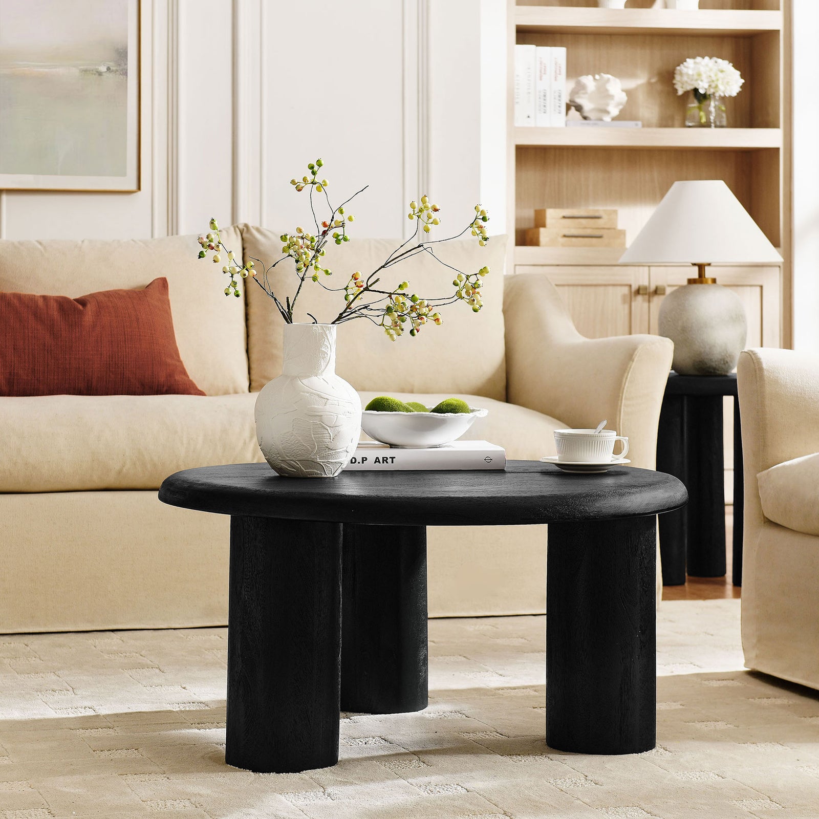 Modern round coffee table anchors the seating area with sculptural three-leg design || EEI-7286-BLK || front_angle_room