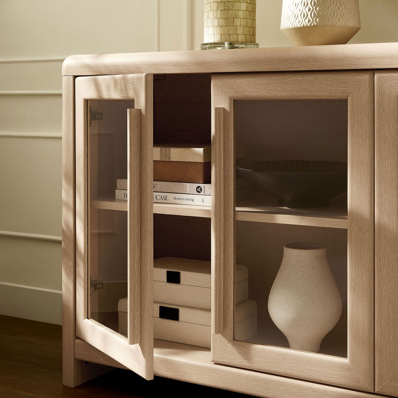 Styled Evren sideboard shelf space with glass doors open to display books, boxes, and decor. || EEI-7287-ASH || storage_open_room