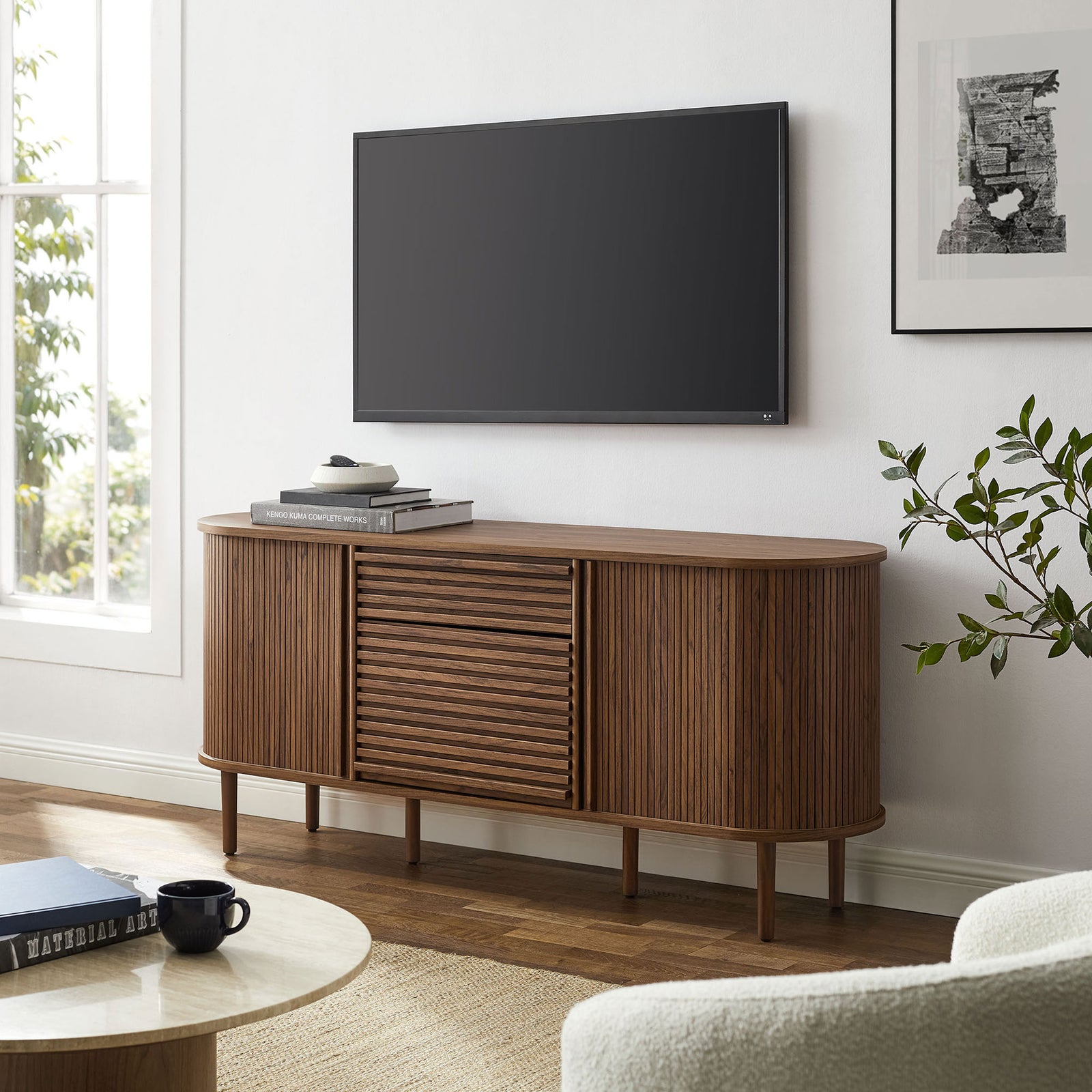 Walnut sideboard serves as a media console beneath a wall-mounted TV with books and decor layered on top || EEI-7293-WAL || front_angle_room