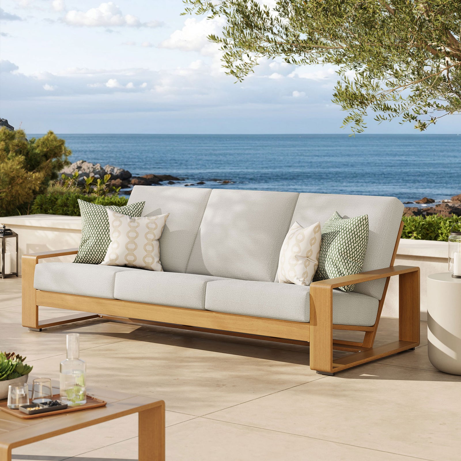 Ivory cushioned outdoor sofa with faux wood frame anchoring a serene coastal patio seating arrangement || EEI-7298-IVO-NAT || front_angle_room