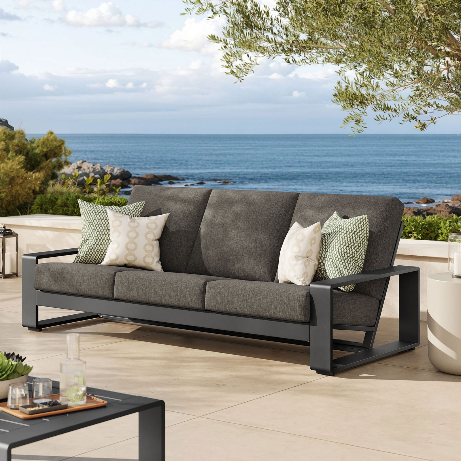 Smoke gray three-seat outdoor sofa on a coastal patio, mixing deep cushioning with a striking dark frame || EEI-7302-SMO-GRY || front_angle_room