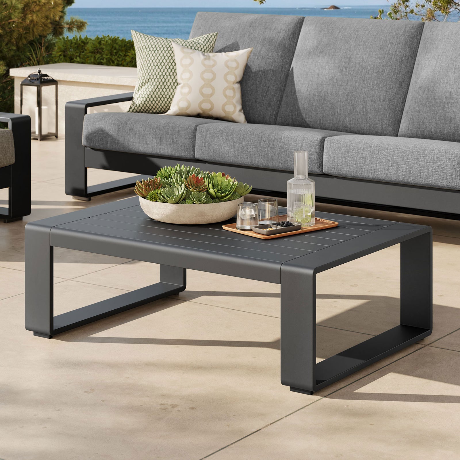 Gray aluminum coffee table paired with matching outdoor sofa on a coastal patio || EEI-7303-GRY || front_angle_room
