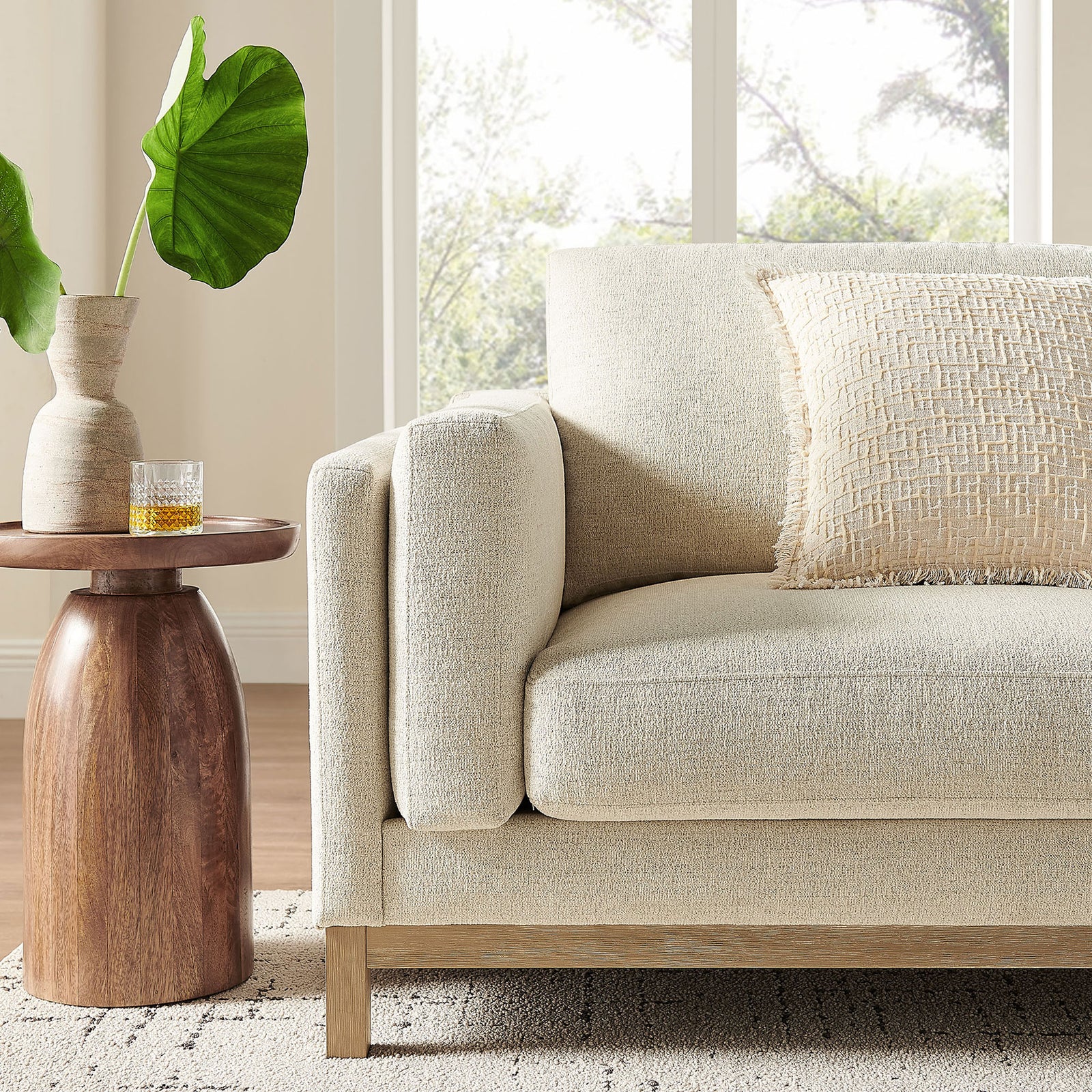 Ivory Roscoe sofa styled with a wood side table, accent pillow, and neutral rug in a bright space || EEI-7327-IVO || detail_room