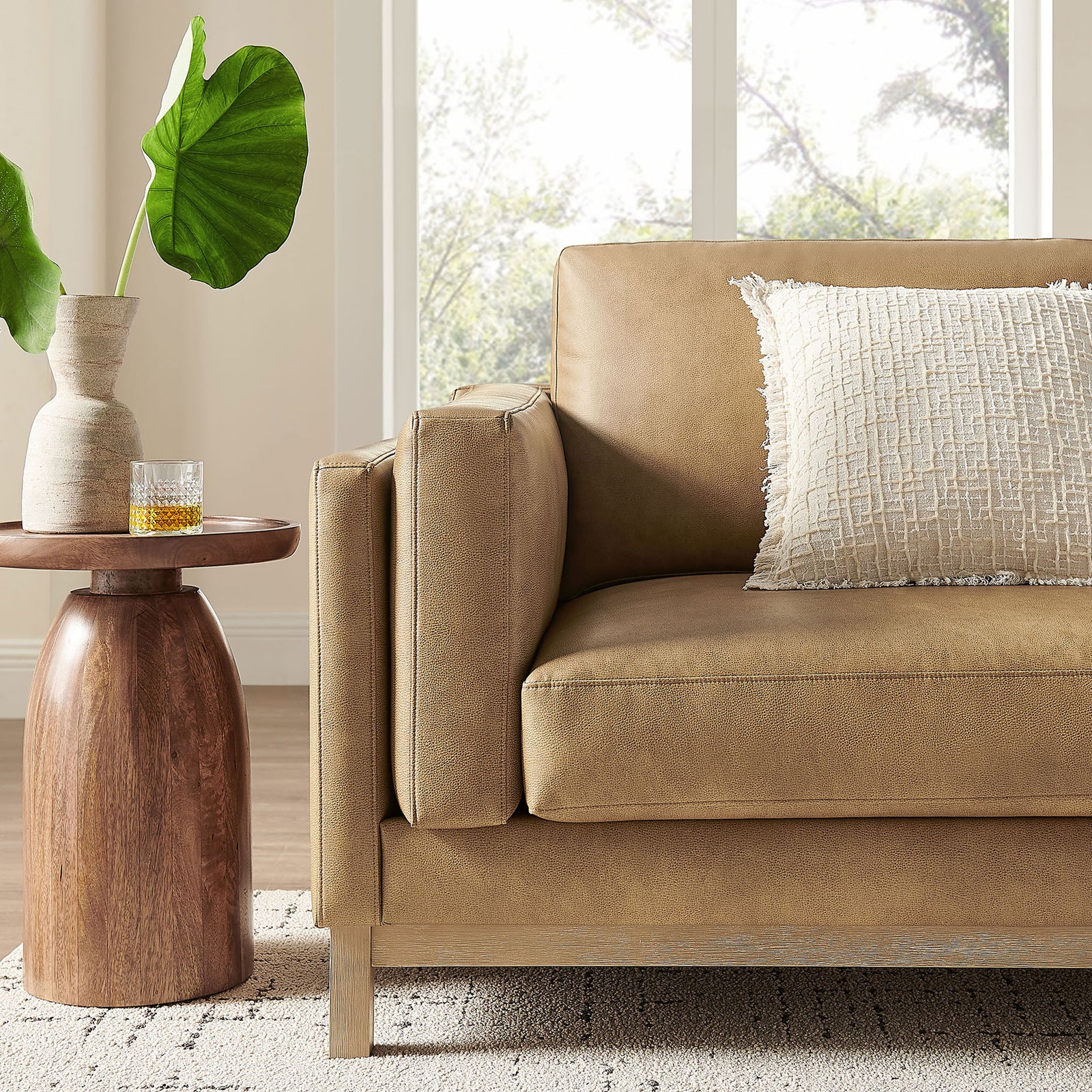 Roscoe toast sofa in a bright living room, paired with textured pillow and a sculptural wood accent table || EEI-7335-TST || detail_room