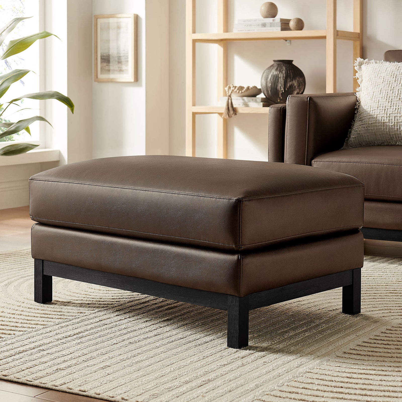 Styled Roscoe ottoman in espresso vegan leather on neutral rug with coordinating sofa and decor. || EEI-7338-ESP || front_angle_room