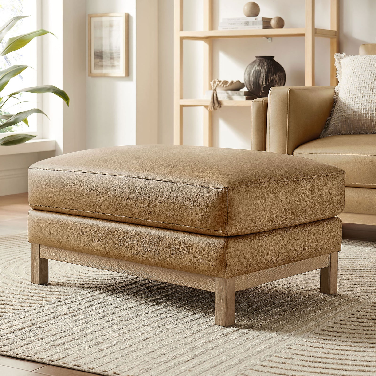 Roscoe toast vegan leather ottoman styled in a bright living room with neutral rug and decor || EEI-7338-TST || front_angle_room