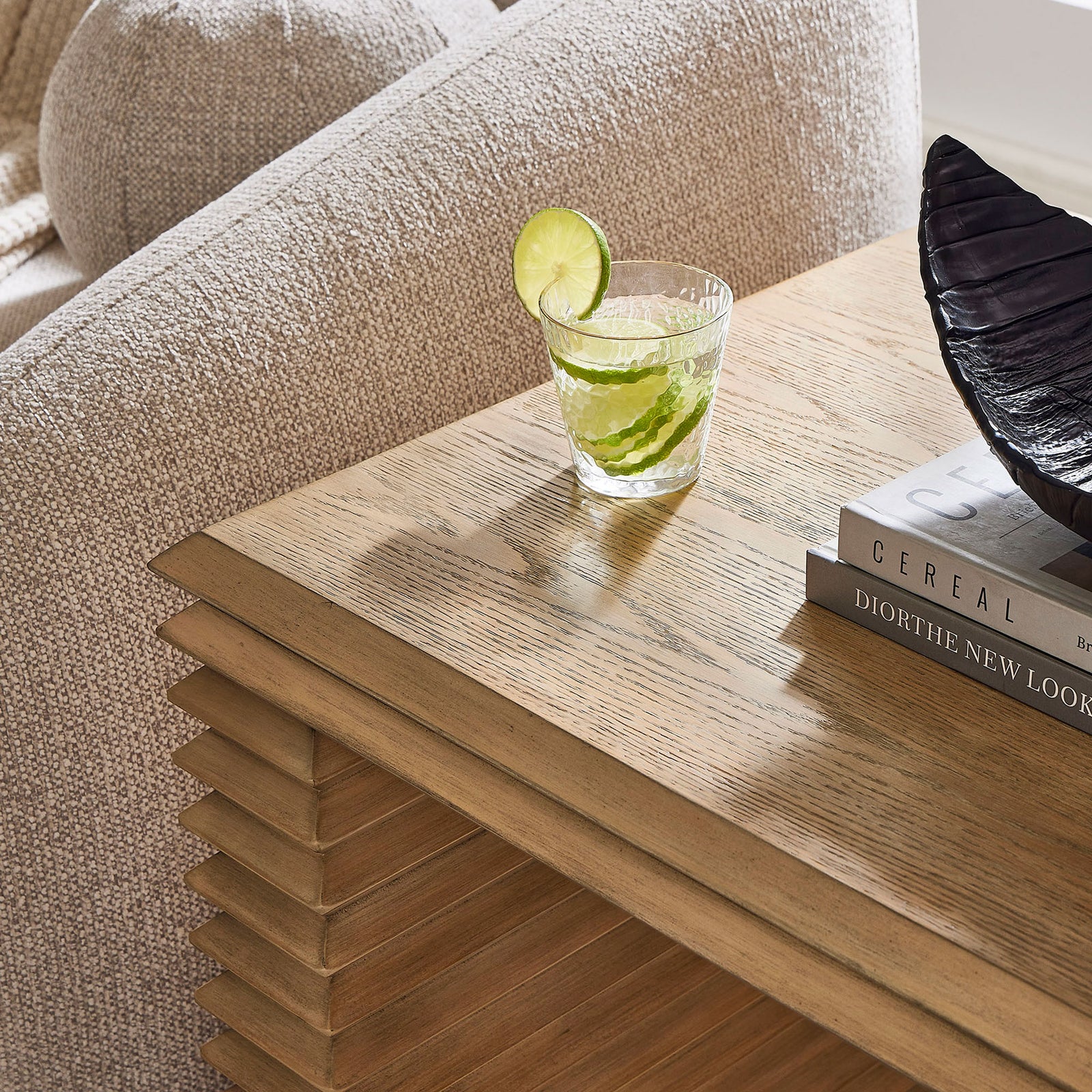 Styled tabletop scene shows the end table in use with drinks, books, and decor on its warm oak surface || EEI-7349-WOA || detail_room