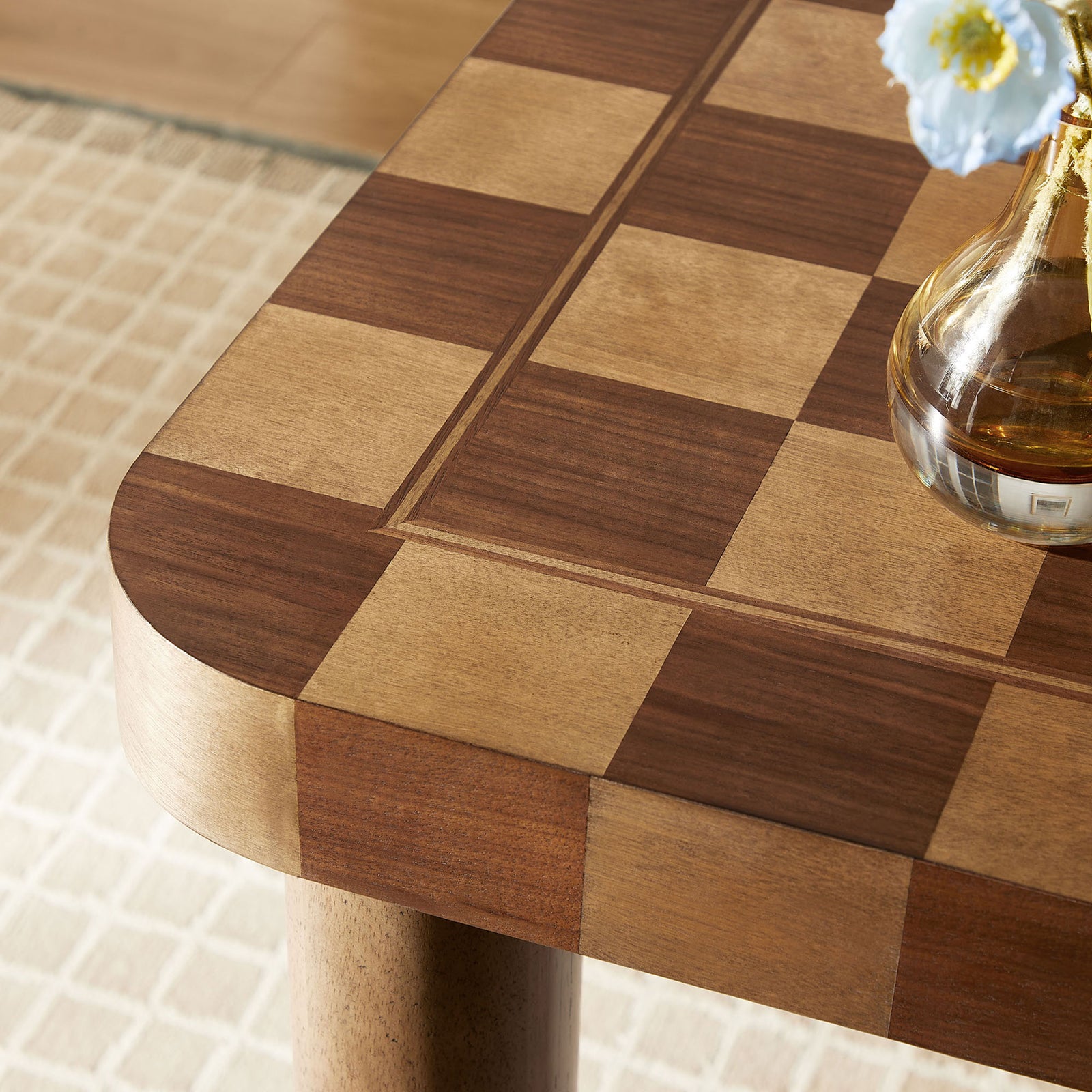 The checkered wood tabletop and rounded corner are styled with a simple glass vase in a softly lit space || EEI-7351-DWC || detail_room