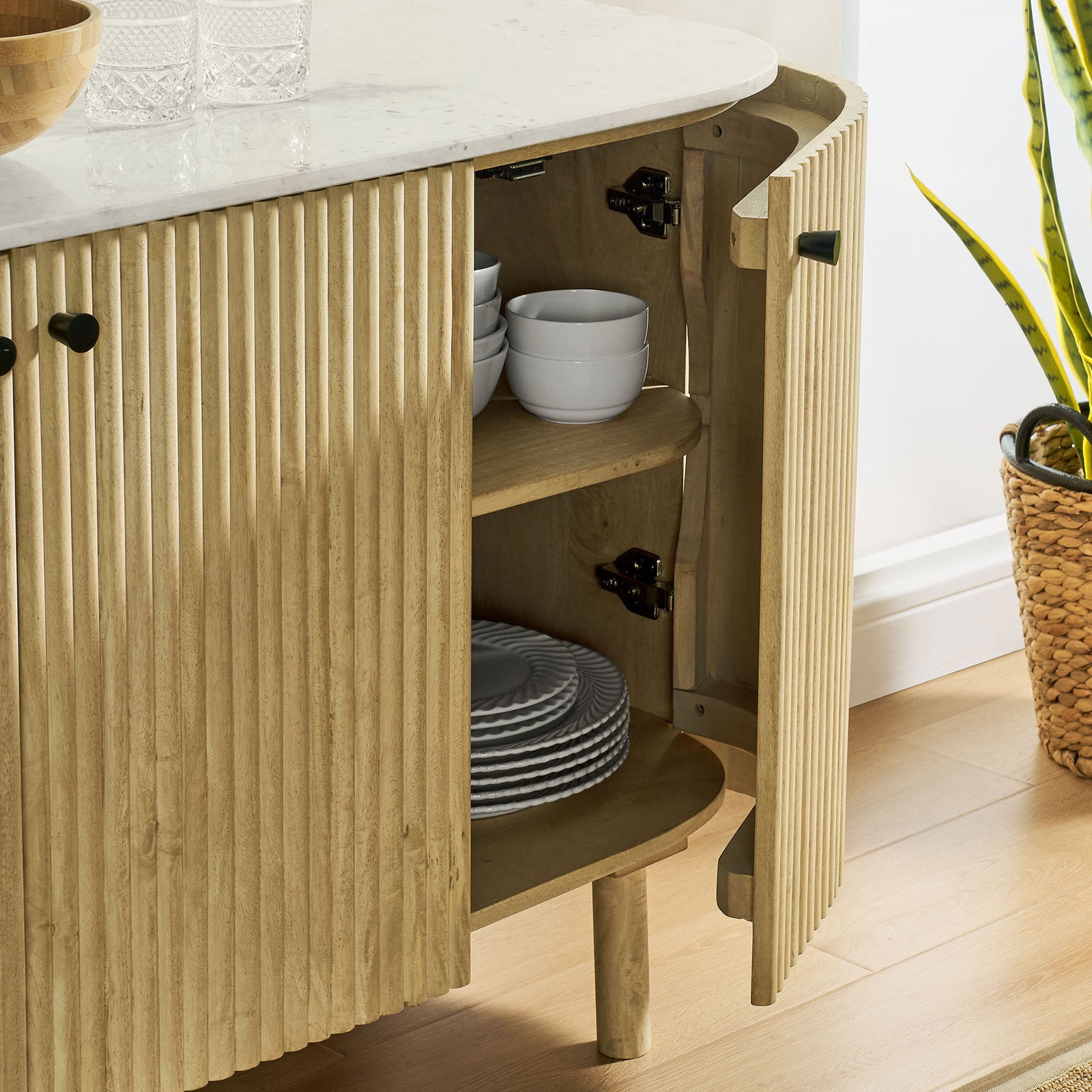 Open cabinet door revealing interior shelves neatly stacked with dishes in a bright modern room || EEI-7355-NAT || storage_open_room
