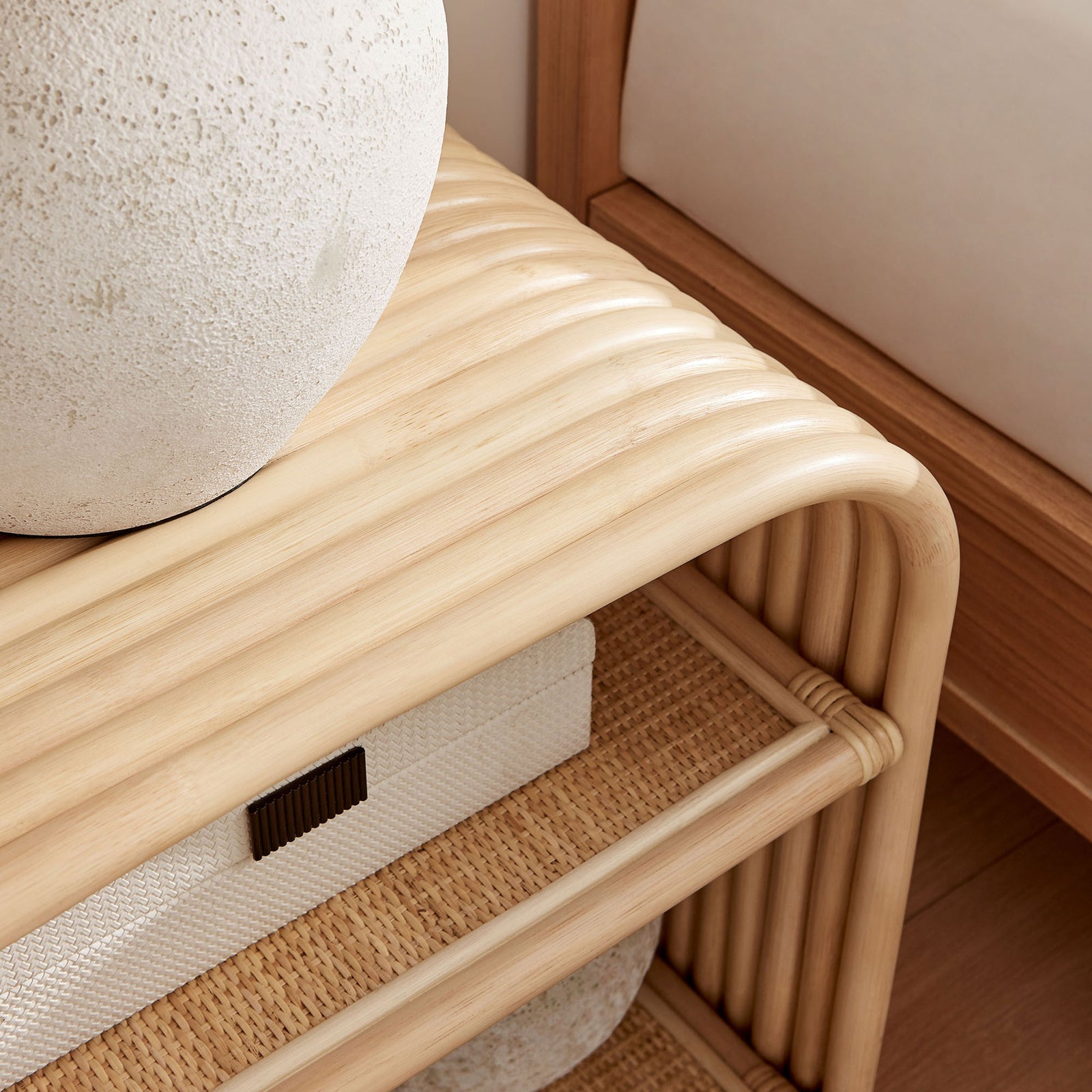 Eve rattan side table styled with stone lamp and storage baskets beside a modern bed || EEI-7361-NAT || detail_room