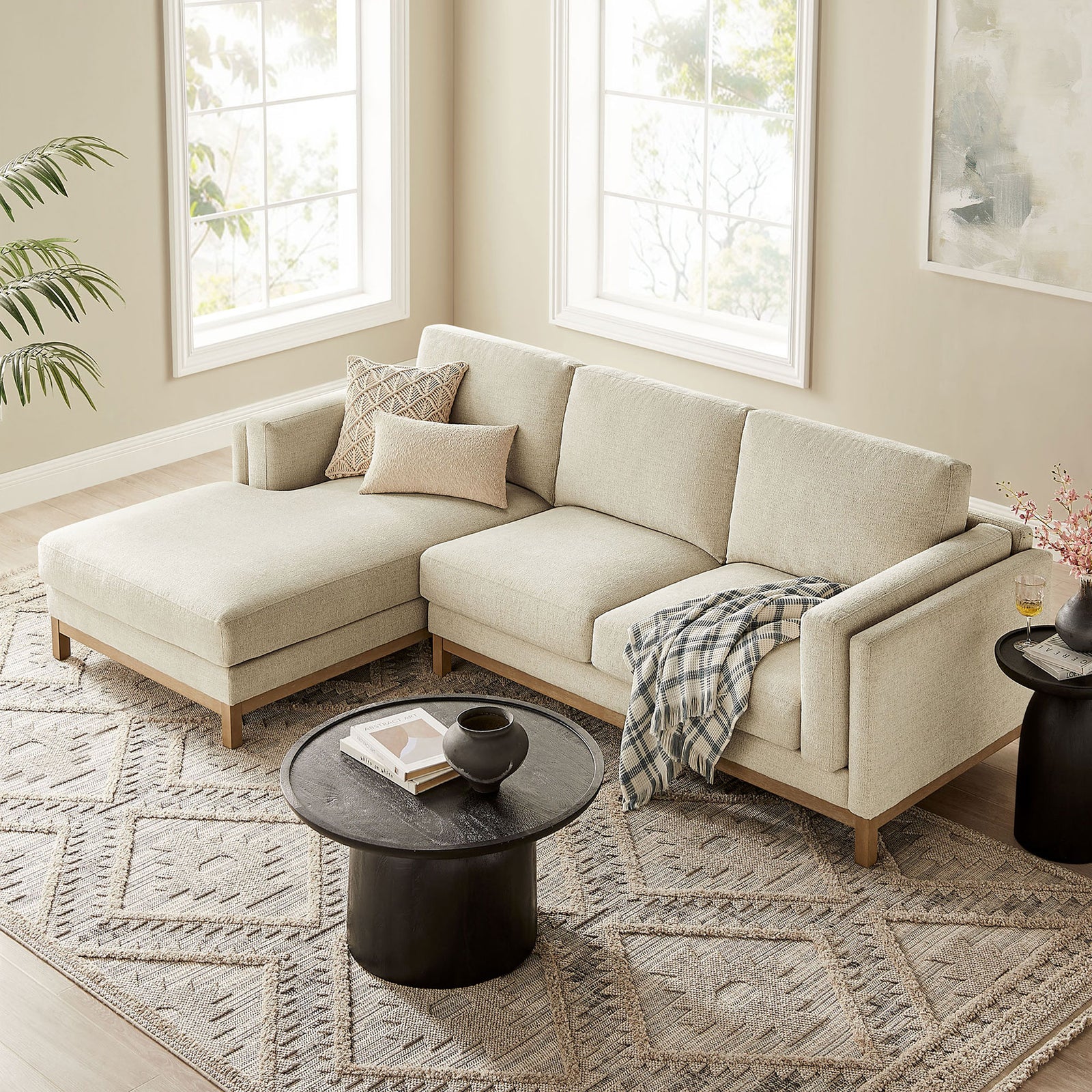 Ivory sectional sofa with left chaise layered over a patterned rug, accented by soft neutral pillows and black table || EEI-7374-IVO || front_angle_room