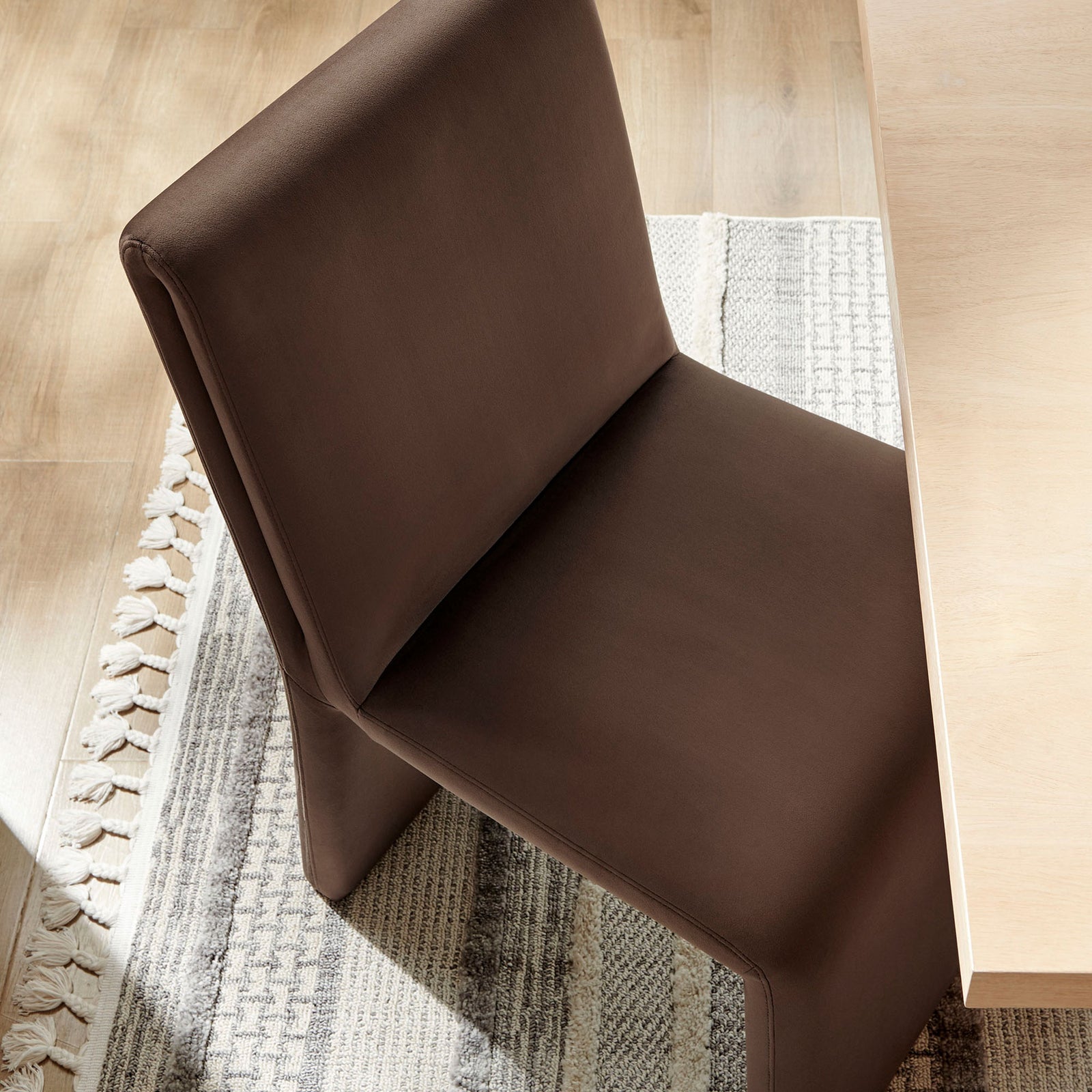 Emory chocolate velvet dining chair styled at a modern wood table, adding rich warmth against a neutral woven rug. || EEI-7384-CHB || front_angle_room