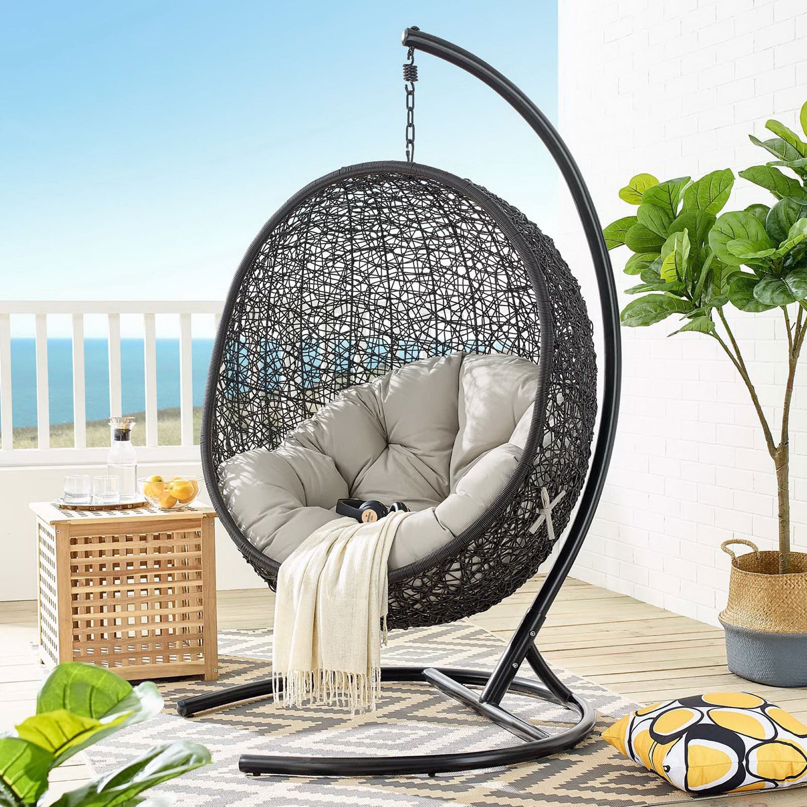 Beige cushioned egg chair with stand creates a relaxing focal point on the coastal patio || EEI-739-BEI-SET || front_angle_room
