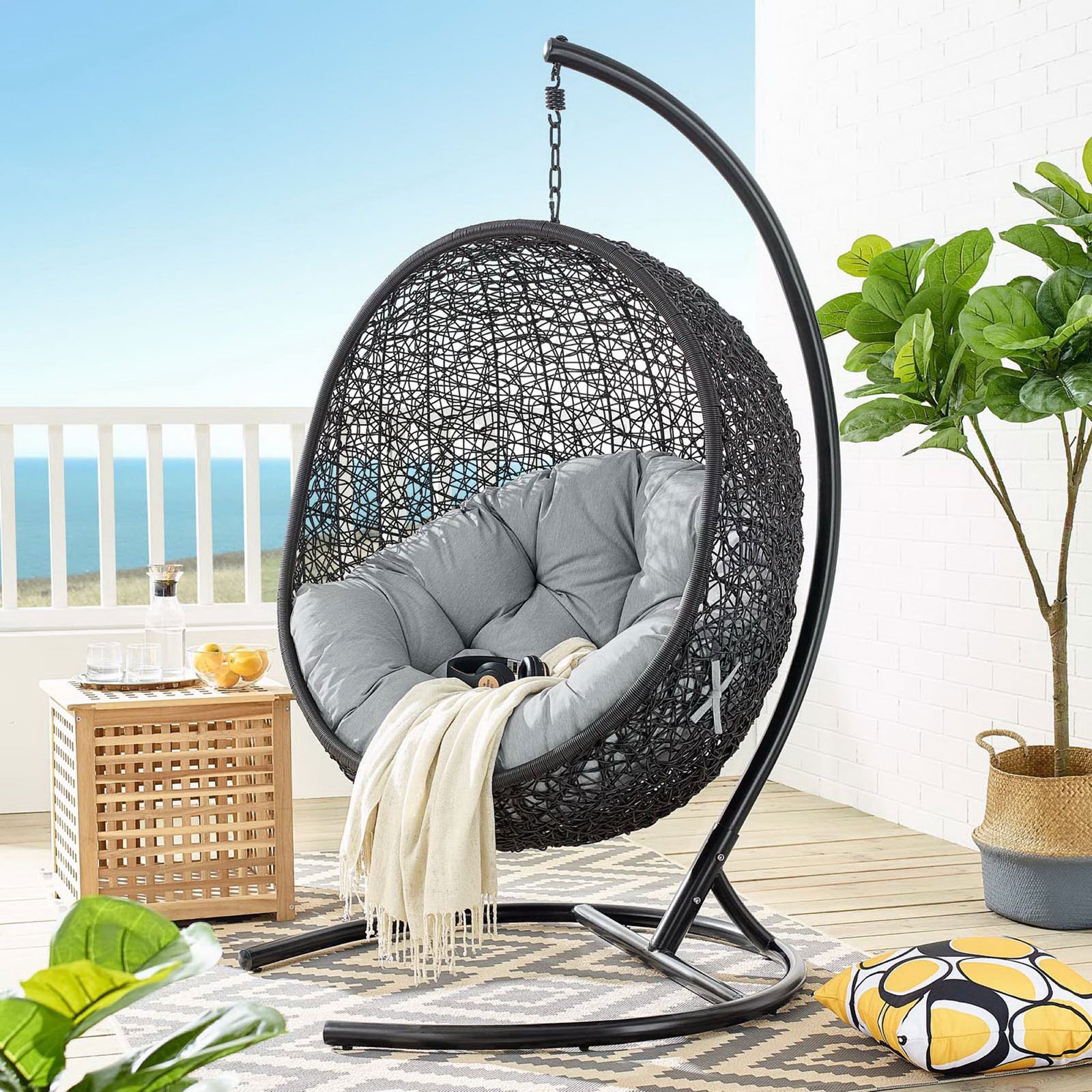 Gray cushioned egg chair with stand anchors a modern coastal balcony lounge || EEI-739-GRY-SET || front_angle_room