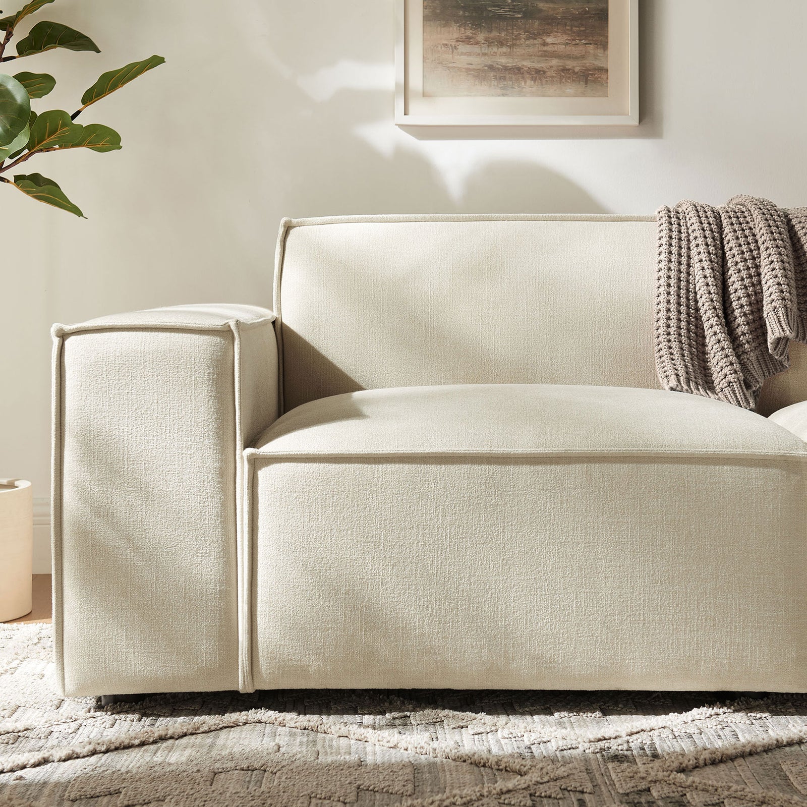 Soft ecru upholstery with French piping and wide armrest, layered with a textured knit throw for added warmth. || EEI-7403-ECR || detail_room
