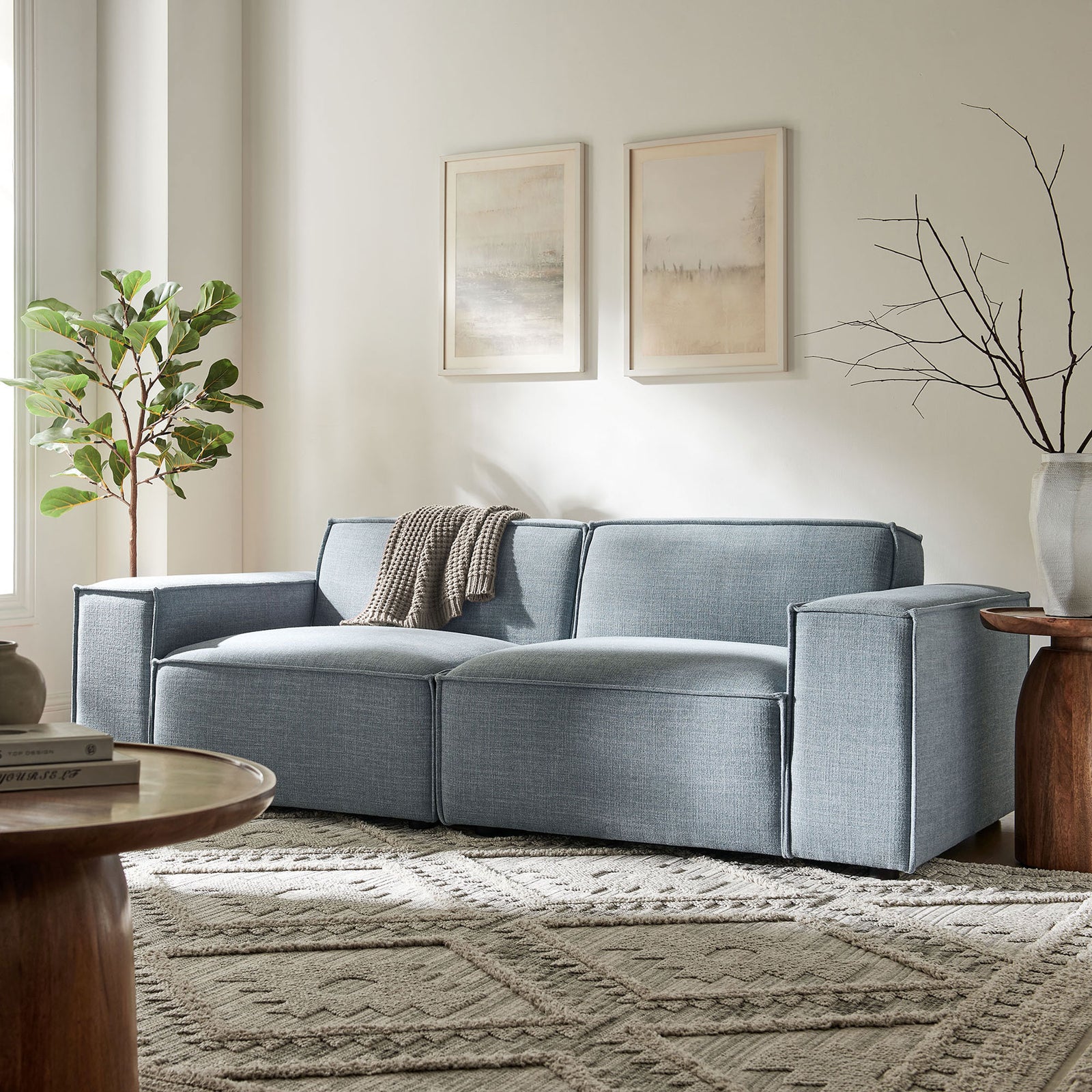 Low-profile sky blue loveseat with wide arms styled beside wood accent tables and greenery || EEI-7403-SKY || front_angle_room