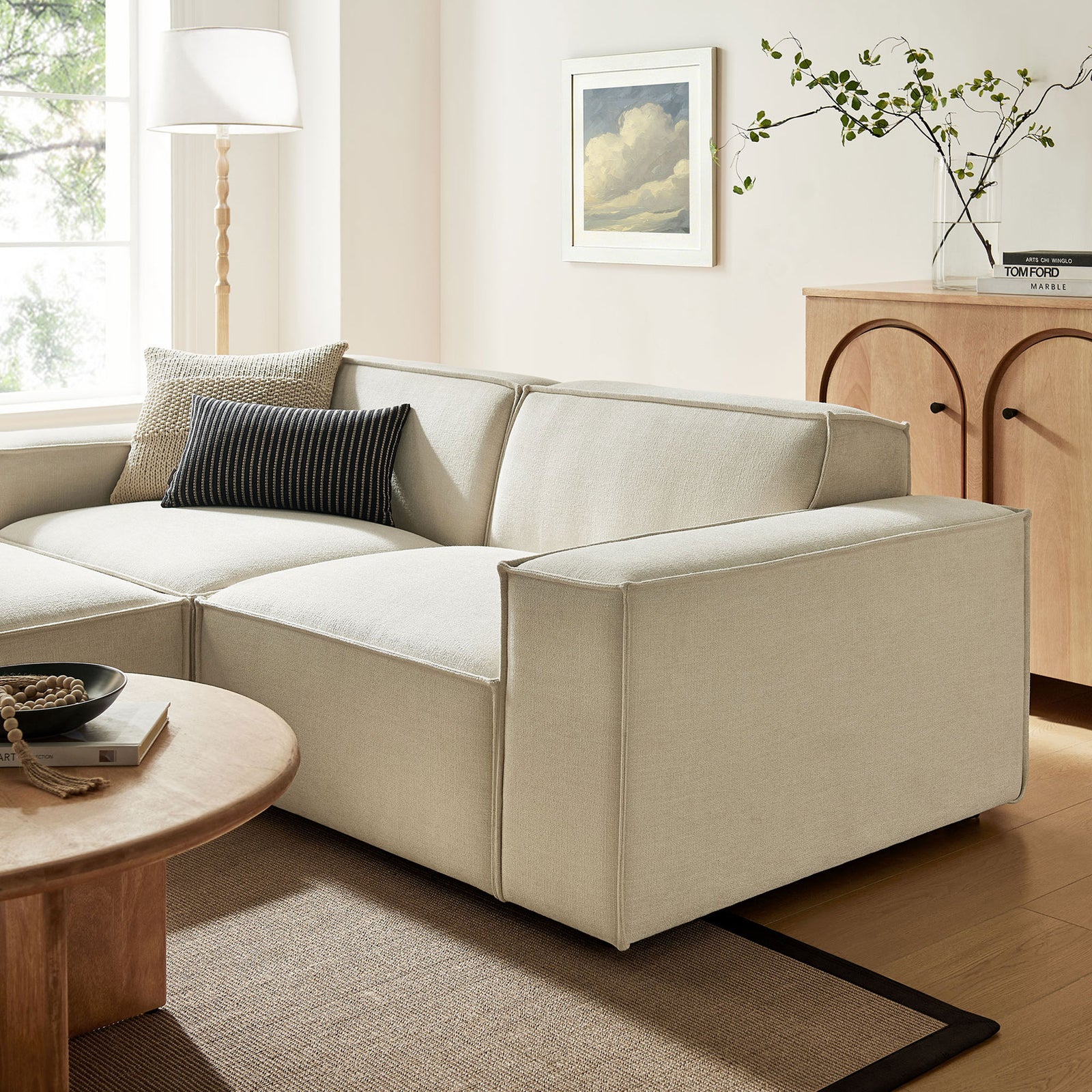 Restore ecru modular loveseat styled in a warm living room with modern wood accents. || EEI-7405-ECR || front_angle_partial_room