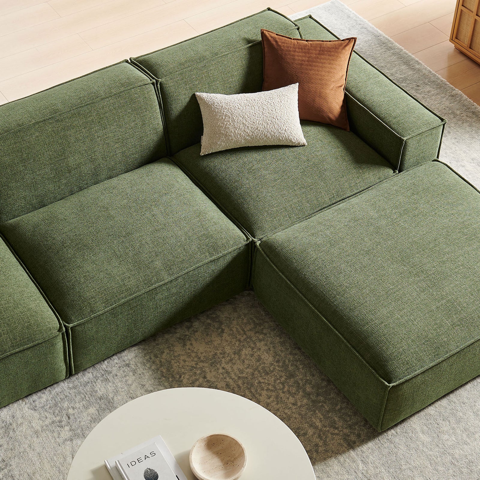 Cozy corner of the green modular sofa styled with accent pillows on a soft area rug || EEI-7409-FOL || detail_room