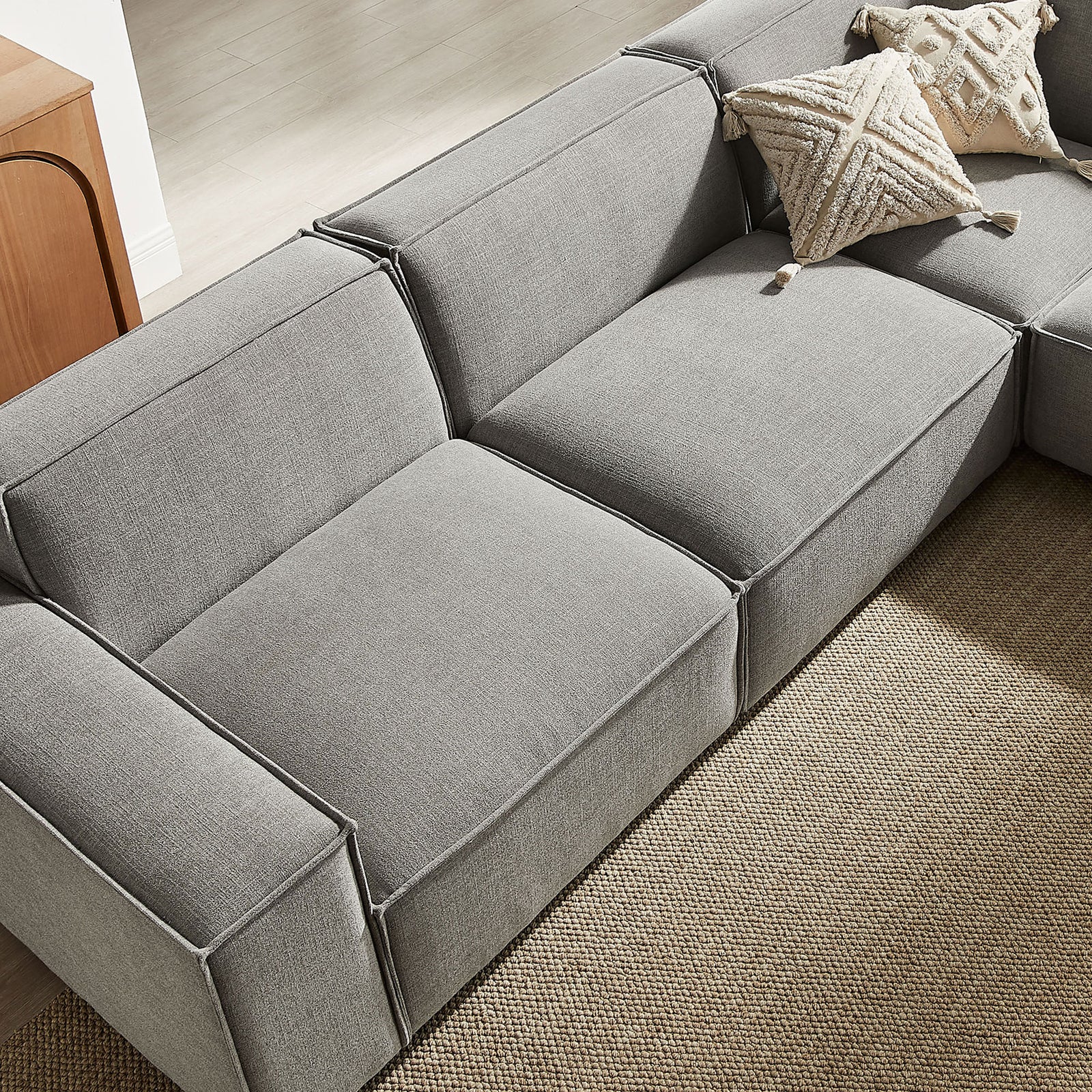 Detail of the sectional back and seat styled with textured throw pillows on a woven rug || EEI-7411-PEW || detail_room