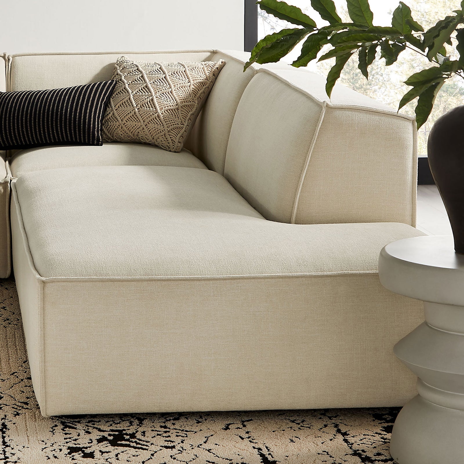 Corner section of the sectional styled with textured pillows, showing the soft supportive backrest. || EEI-7413-ECR || detail_room